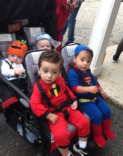 Three children in costumes in a stroller