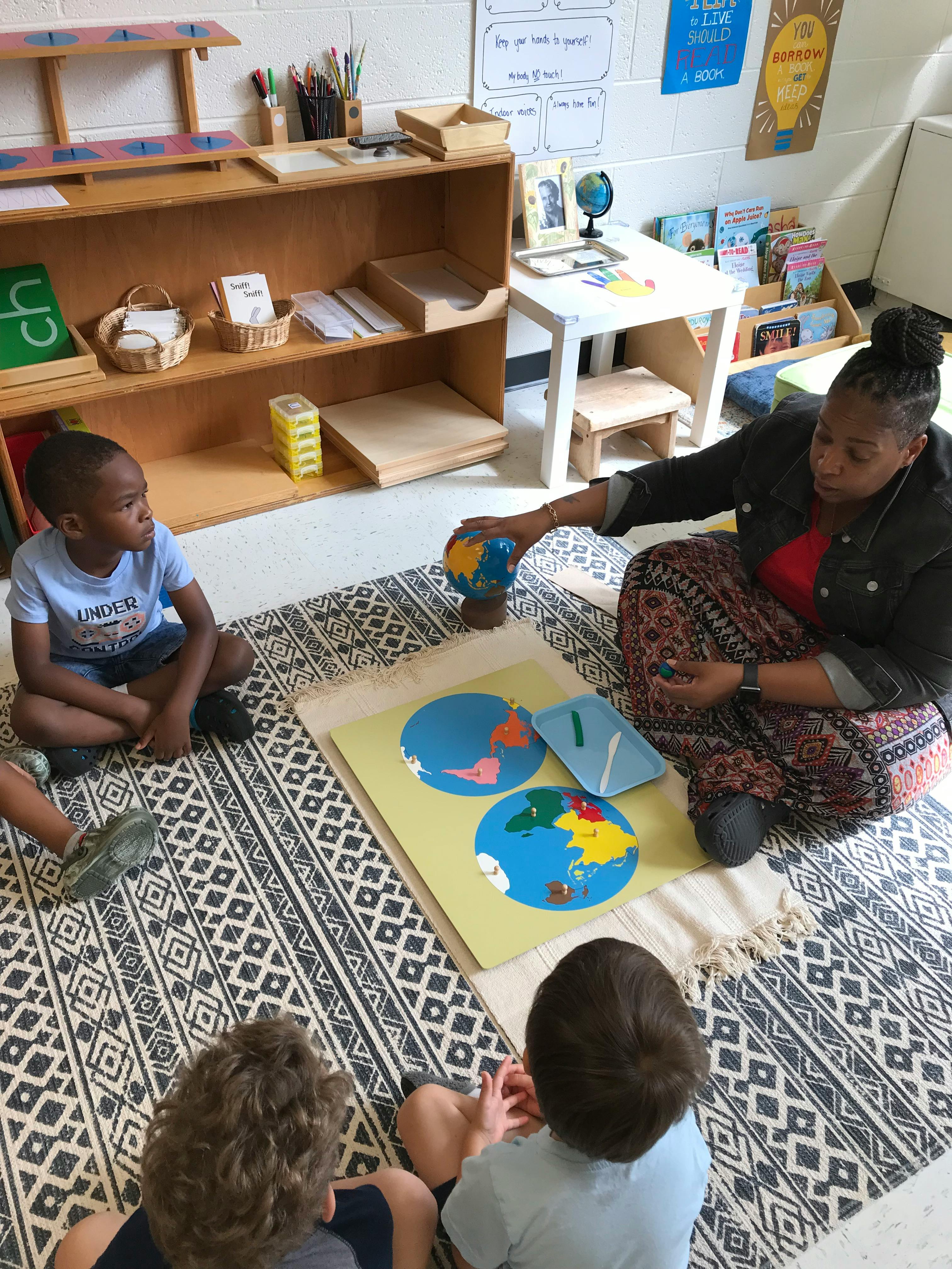 Adult and children sitting on a rug with a globe and world map puzzle