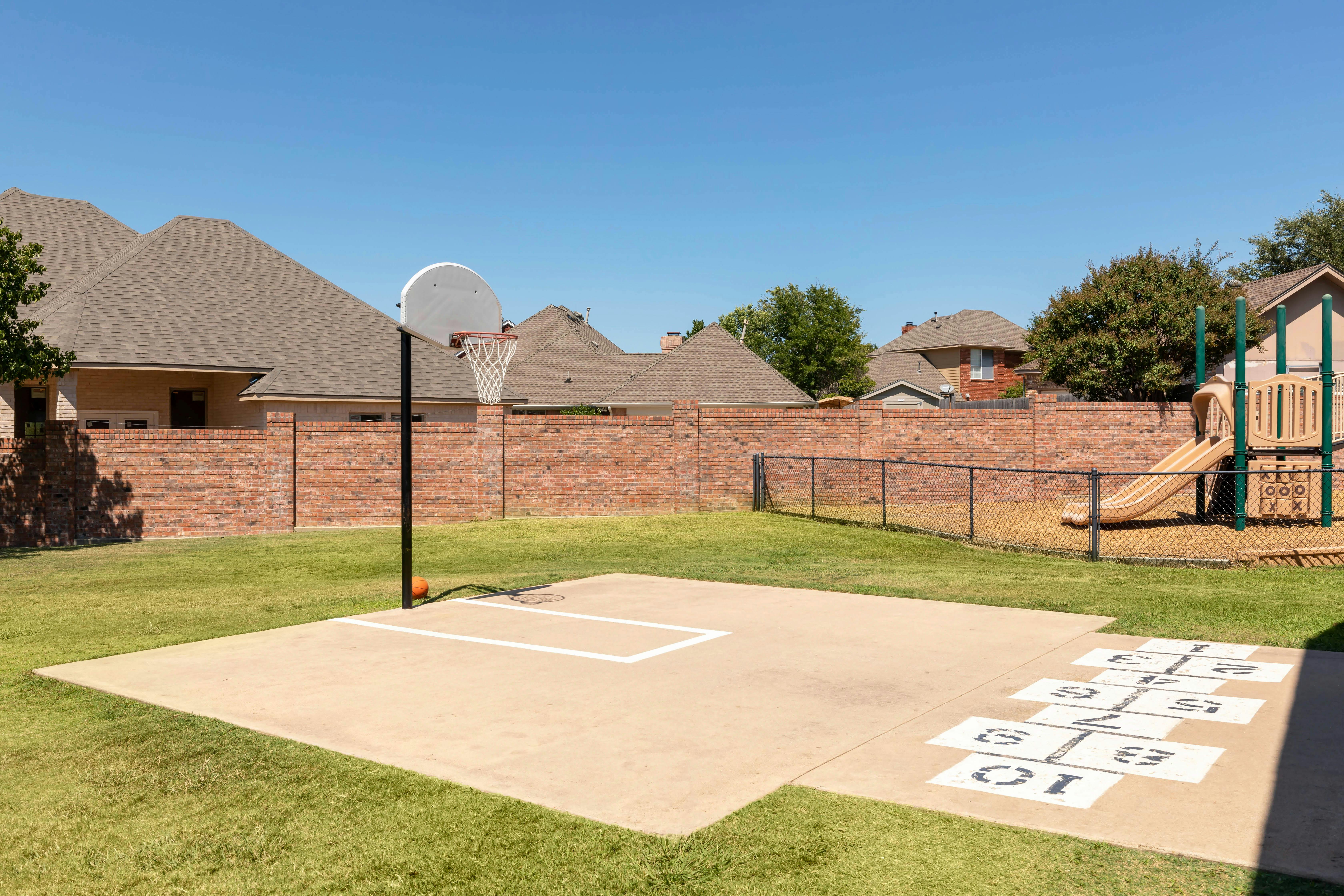 Basketball hoop with a hopscotch court and playground in a backyard