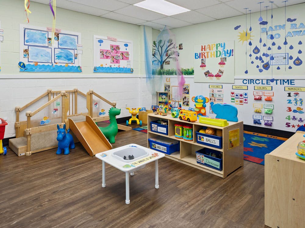 Colorful playroom with a small slide, toys, and educational posters on the walls