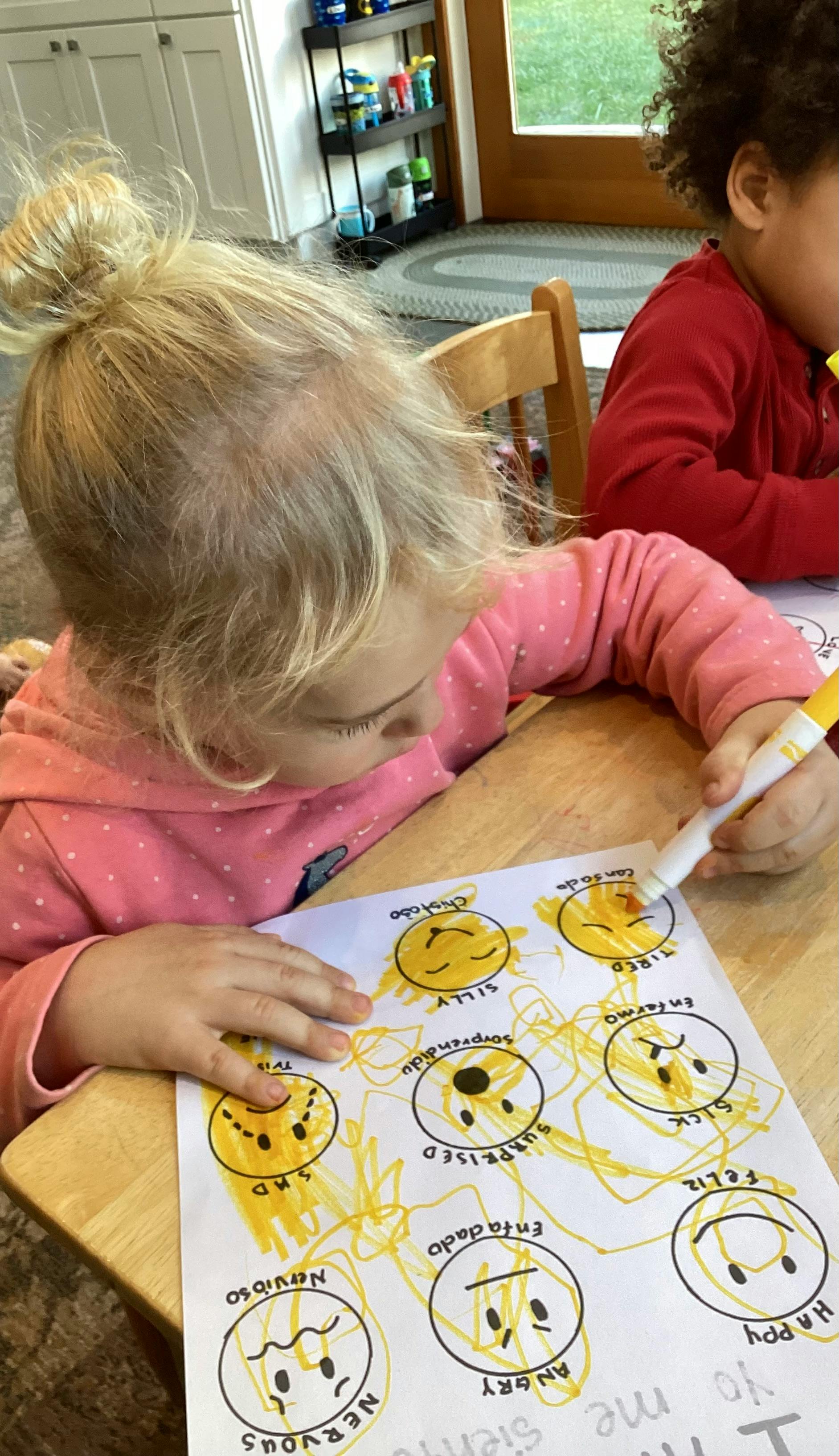 Child coloring a worksheet with different facial expressions