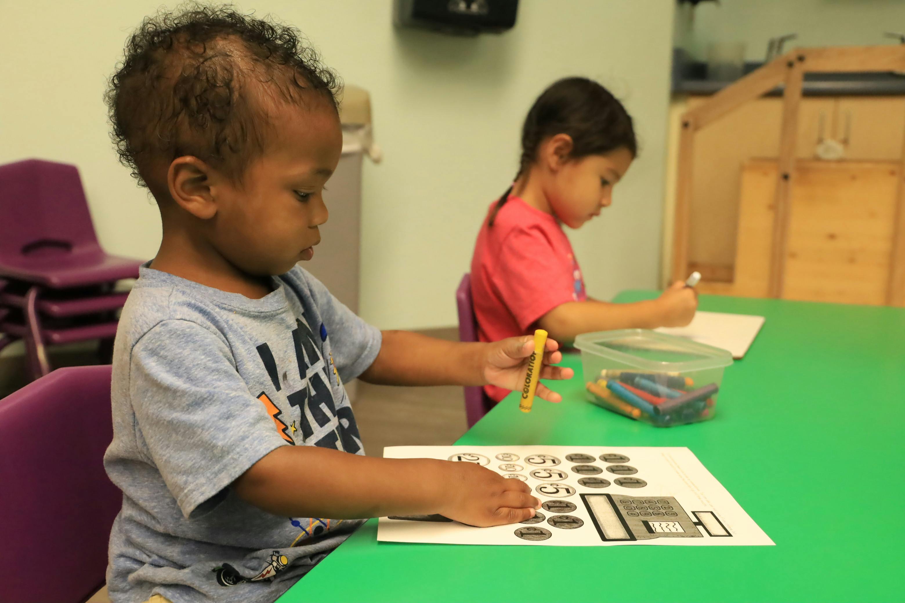 Two children drawing and coloring at a table
