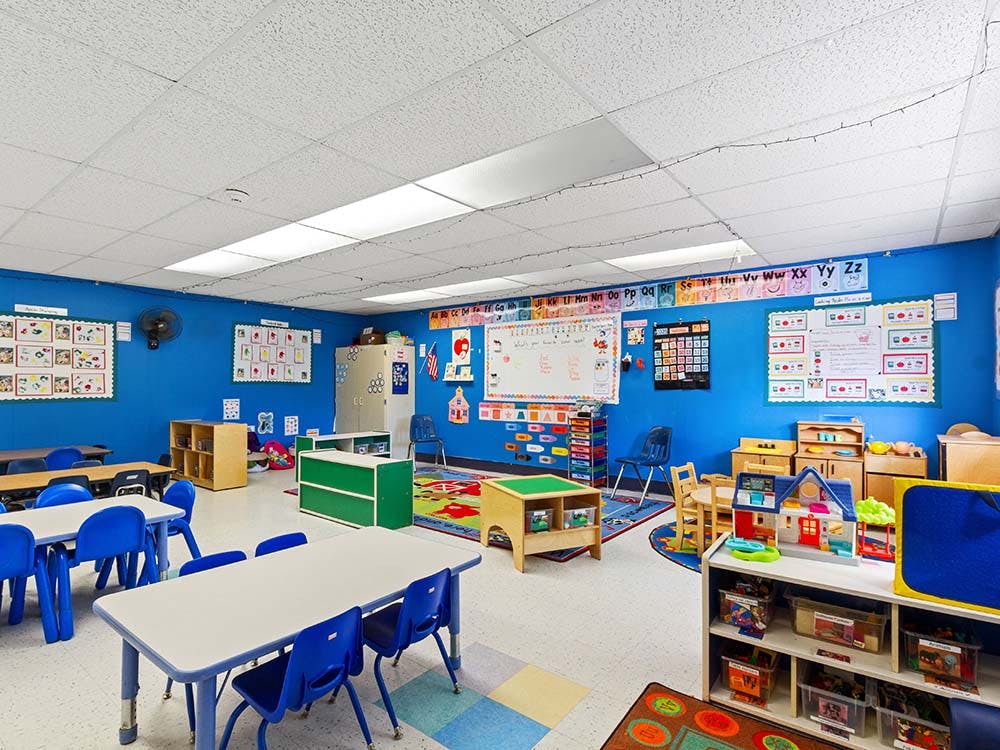 Empty colorful children's classroom with blue walls, tables, and play areas