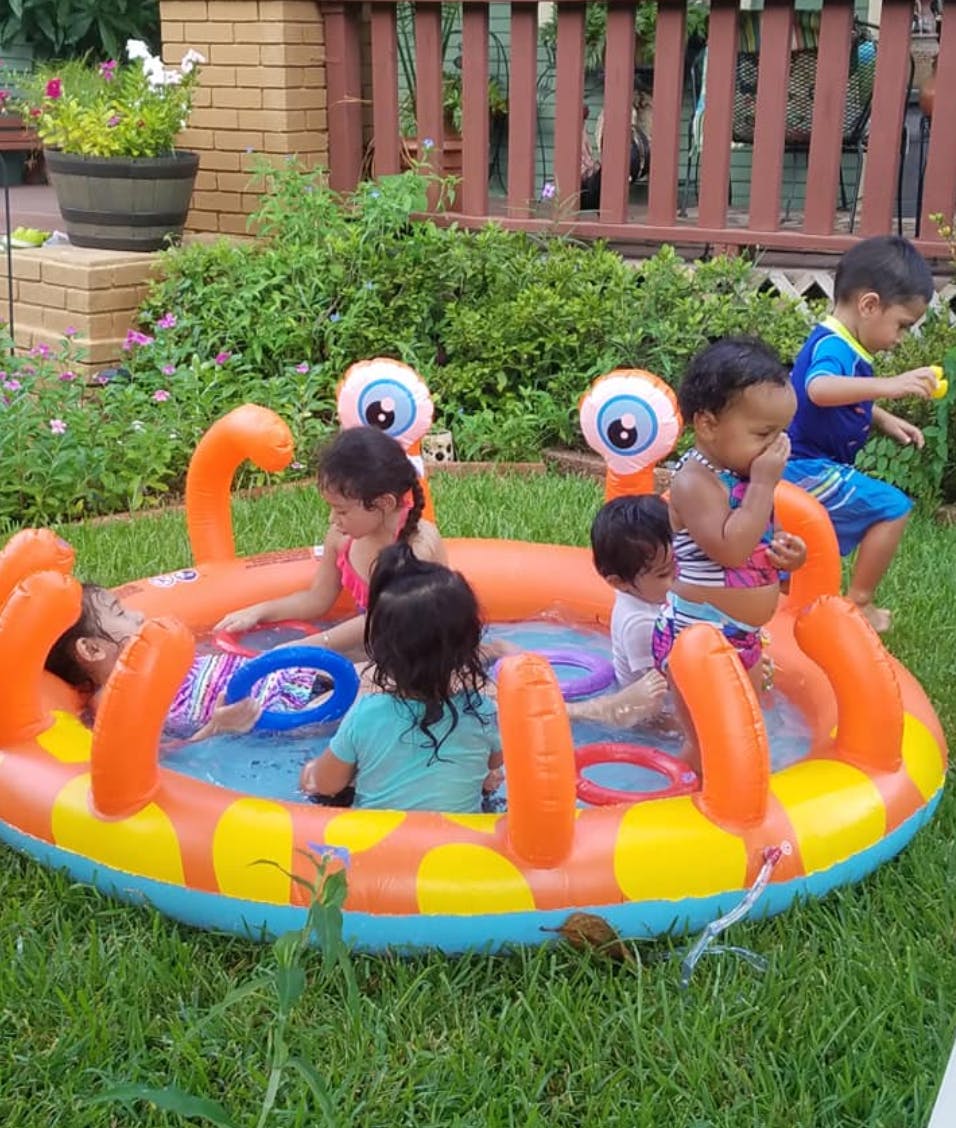Children playing in an inflatable pool in a grassy yard