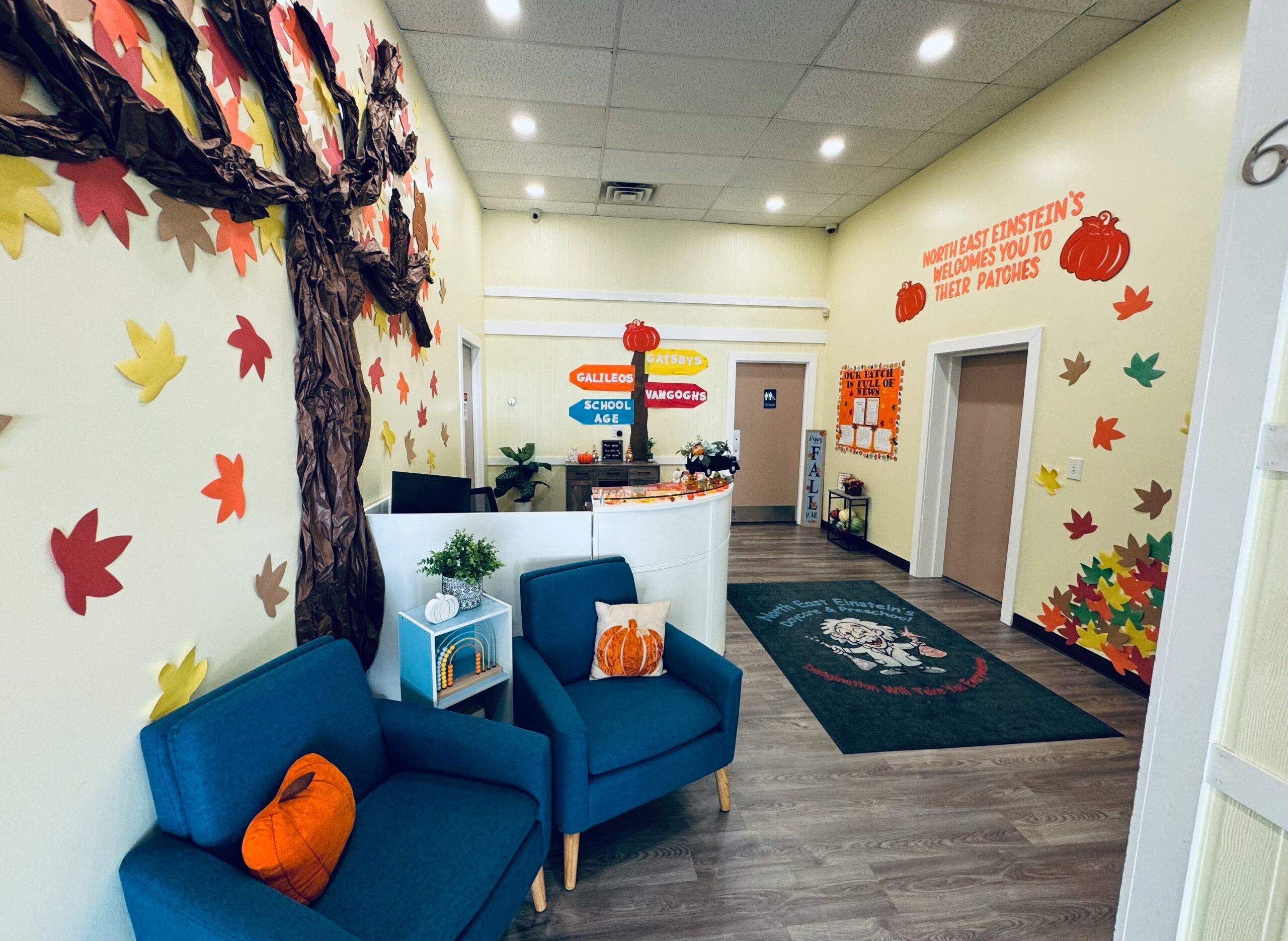 Lobby with fall decorations, two blue chairs, and a reception desk