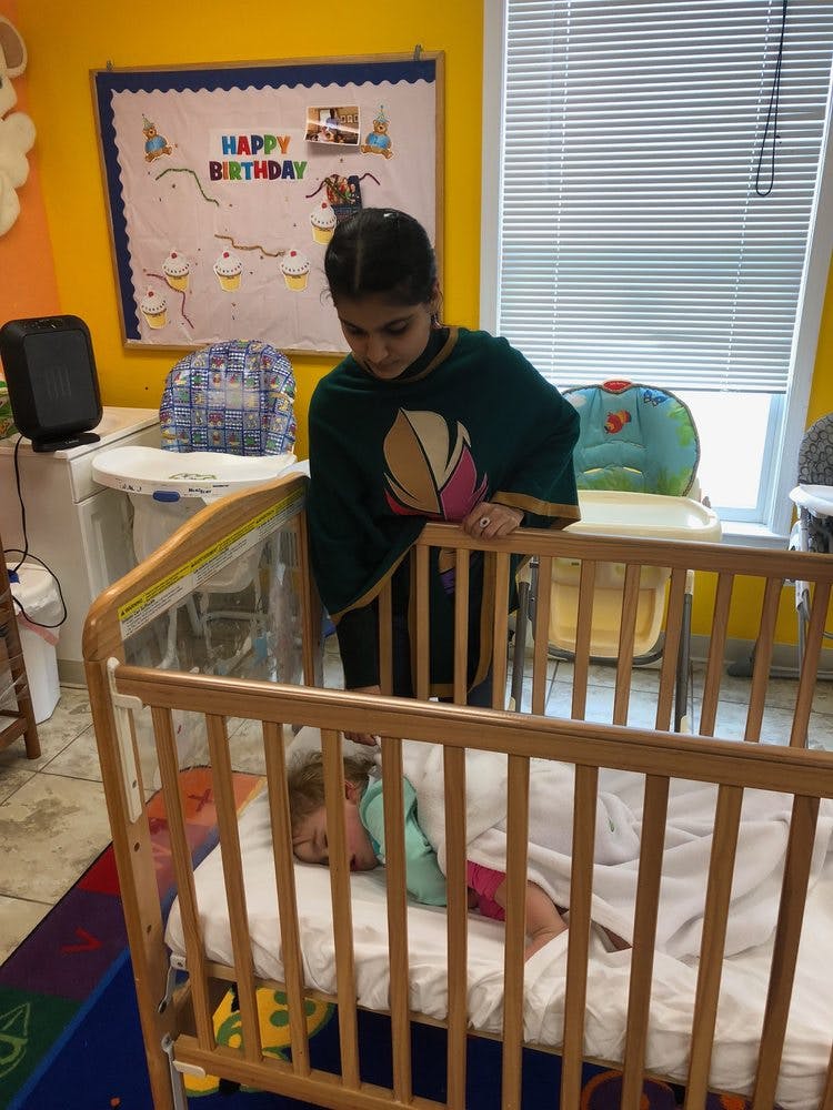 Person looking down at a child sleeping in a crib