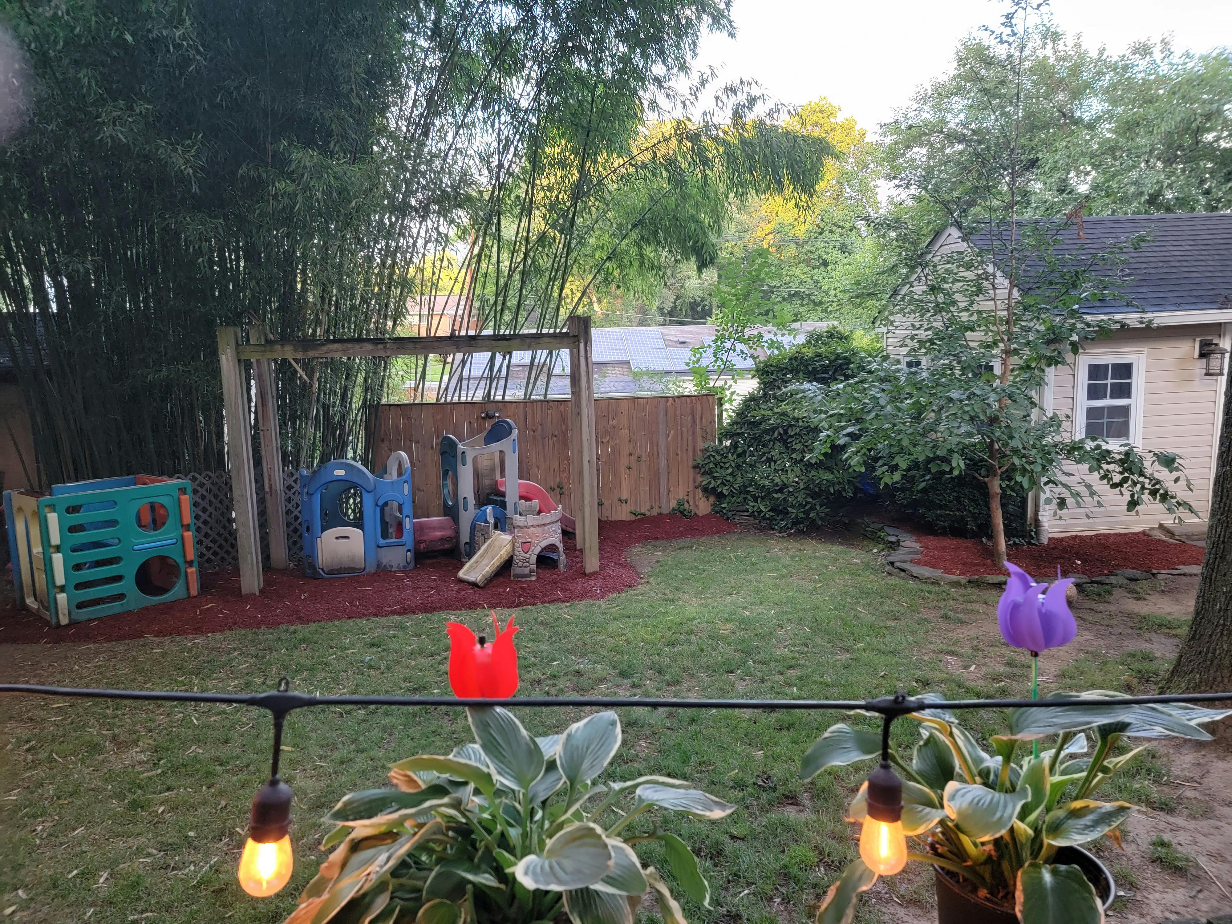 Backyard with a wooden fence, play structure, and small house