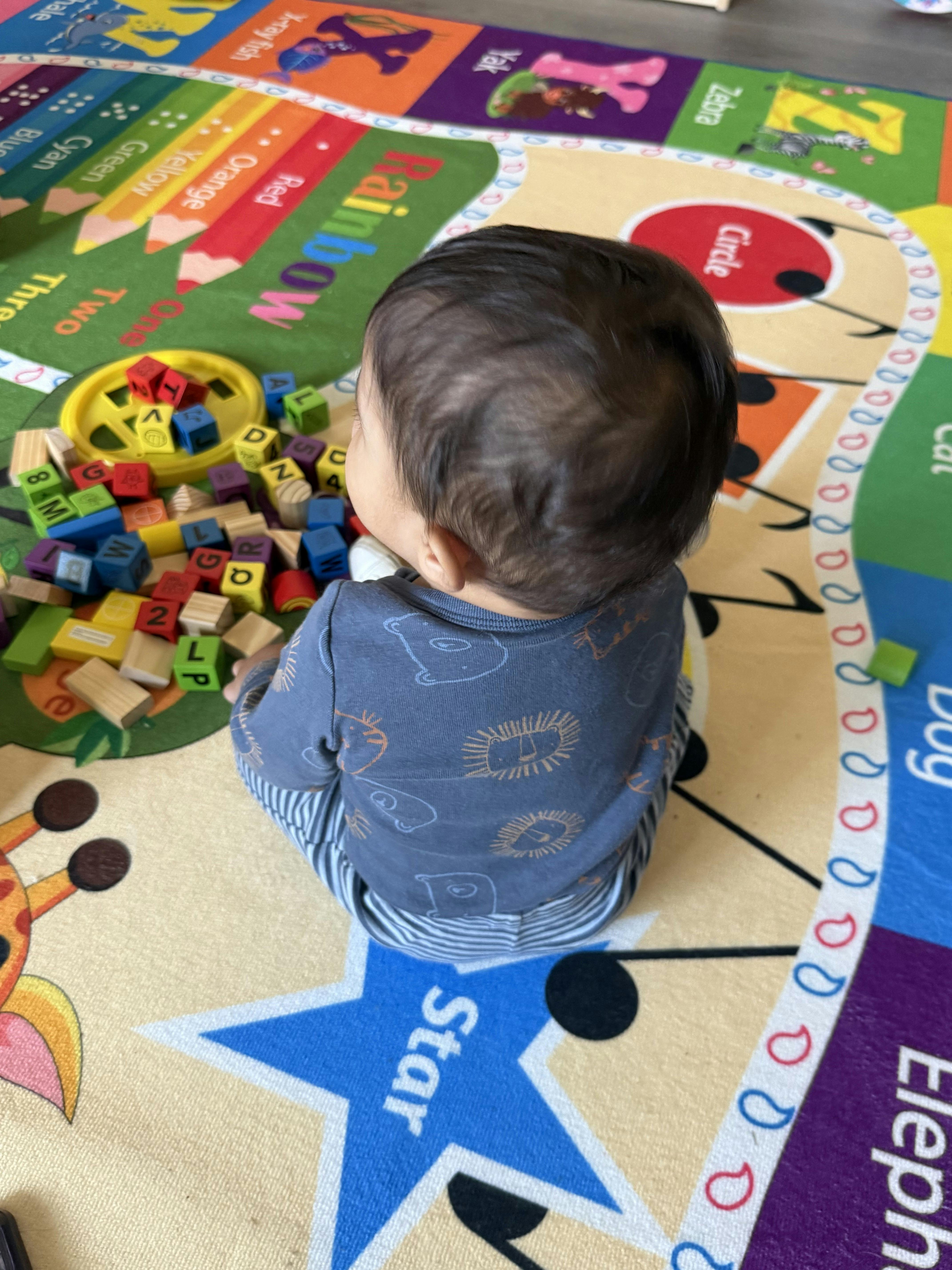 Child sitting on a colorful playmat with alphabet blocks