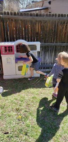 Child reaching into a playhouse with other children nearby