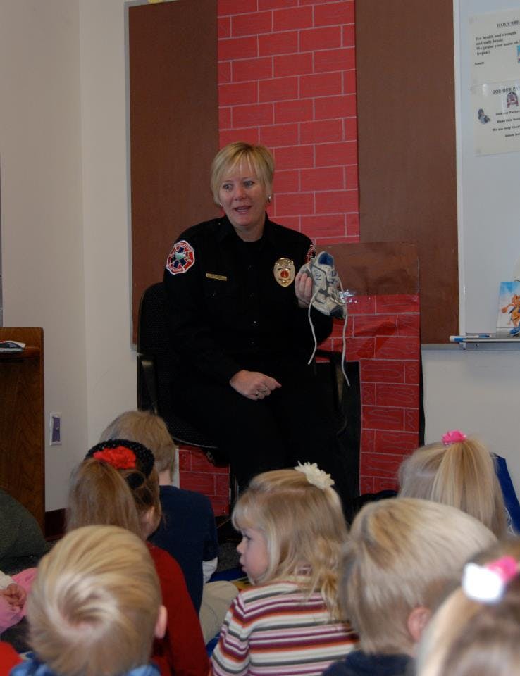 Person in uniform speaking to a group of children