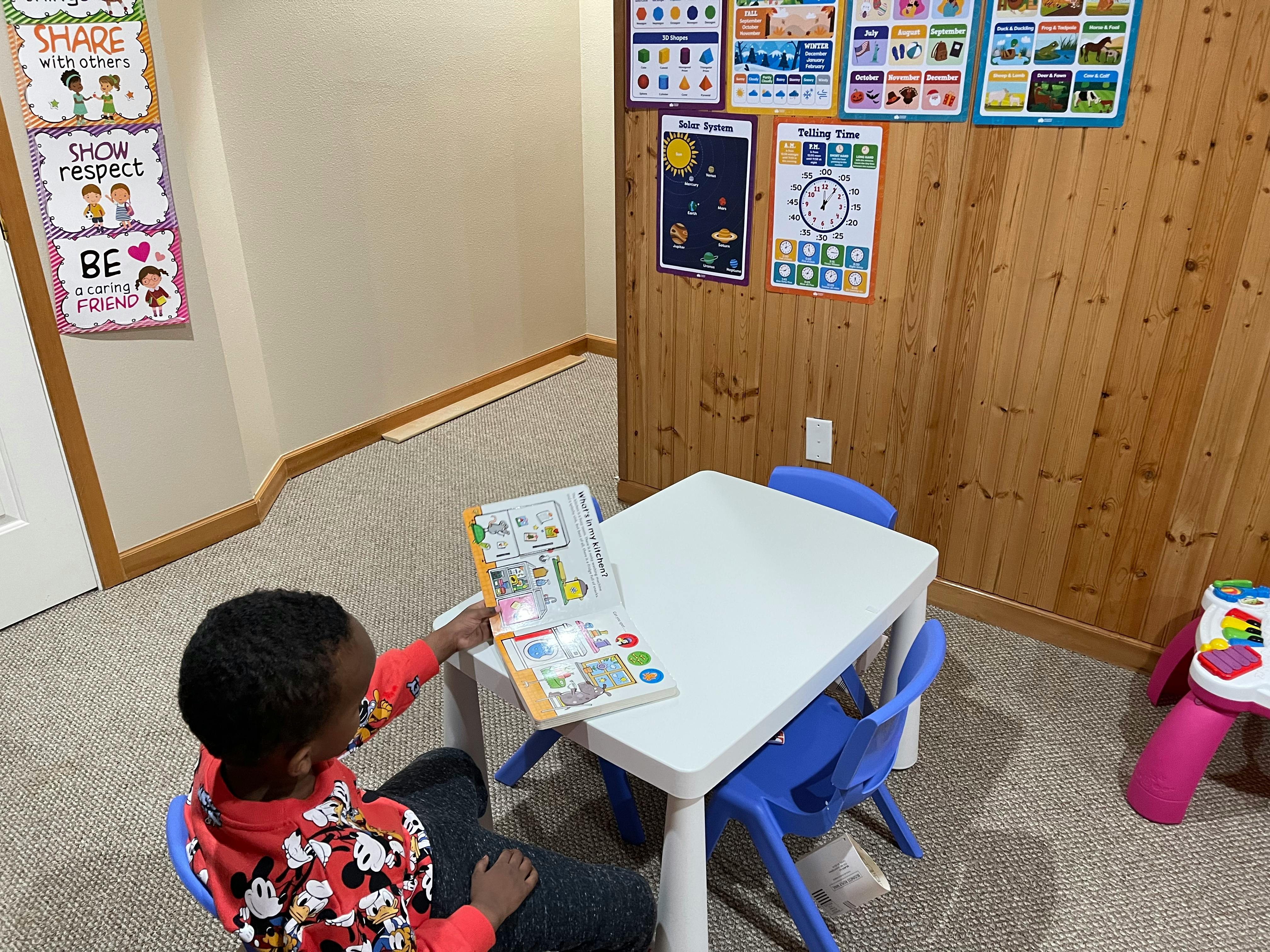 Child sitting at a table looking at a book