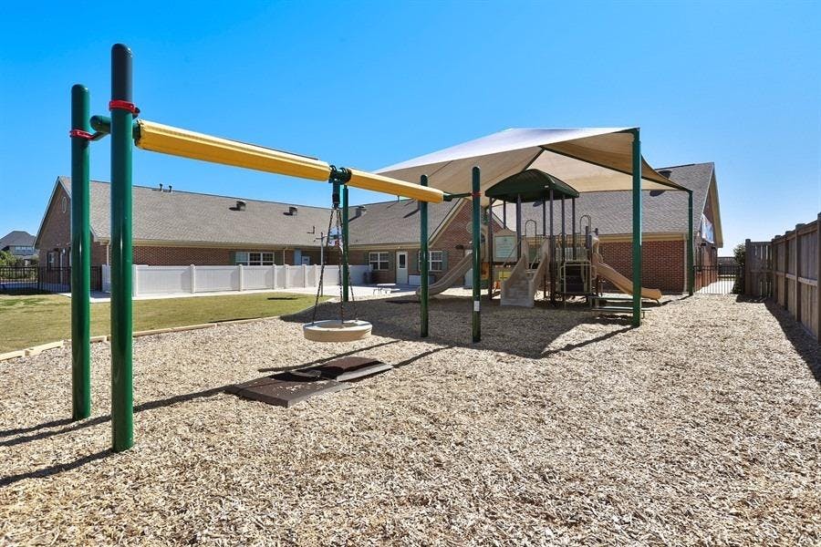 Playground with swings and climbing structure under a shade canopy