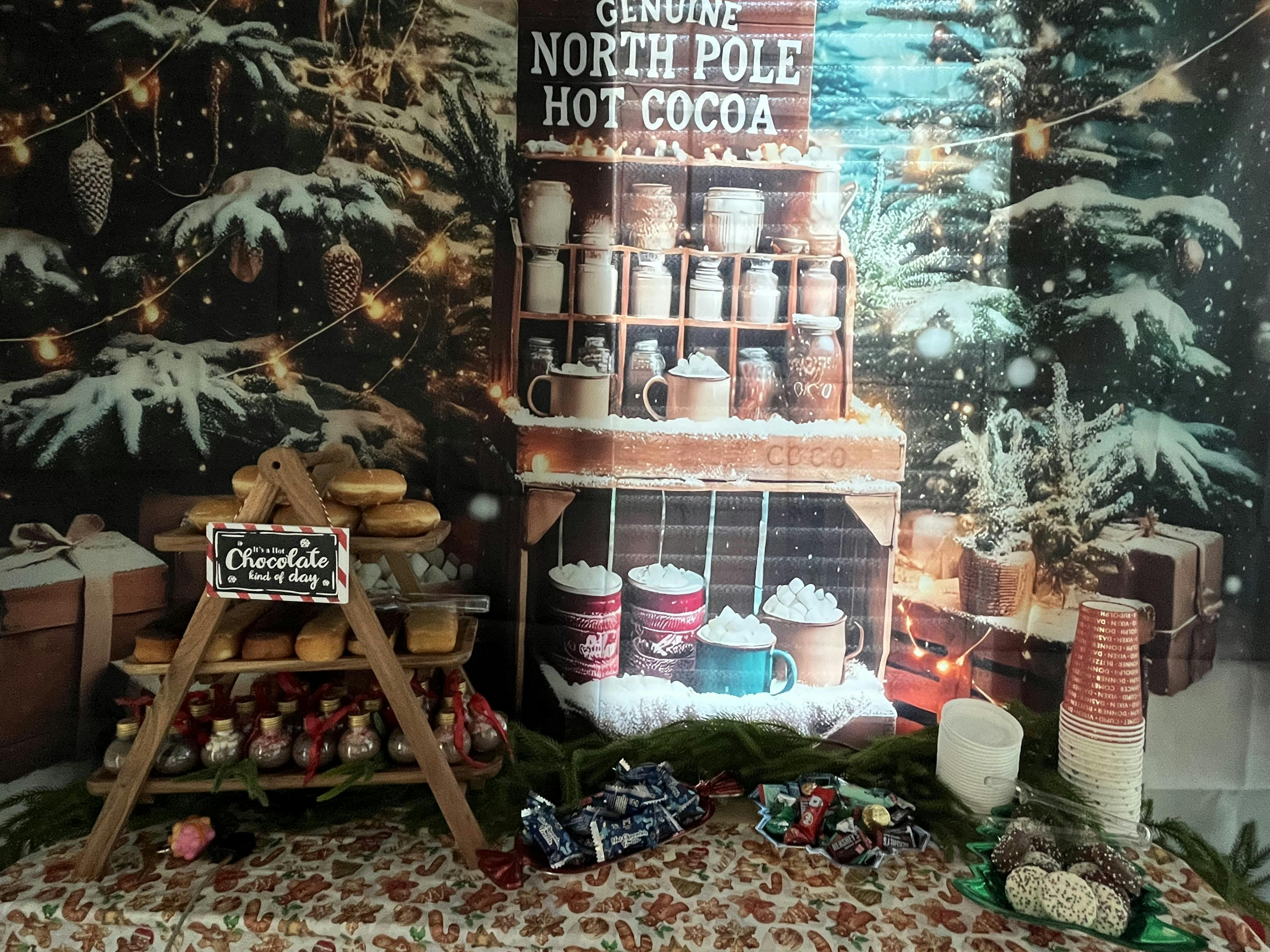 Hot cocoa bar display with donuts and candy set against a festive backdrop