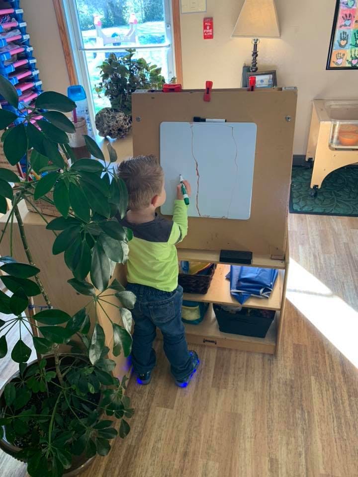 Child drawing on a whiteboard in a classroom