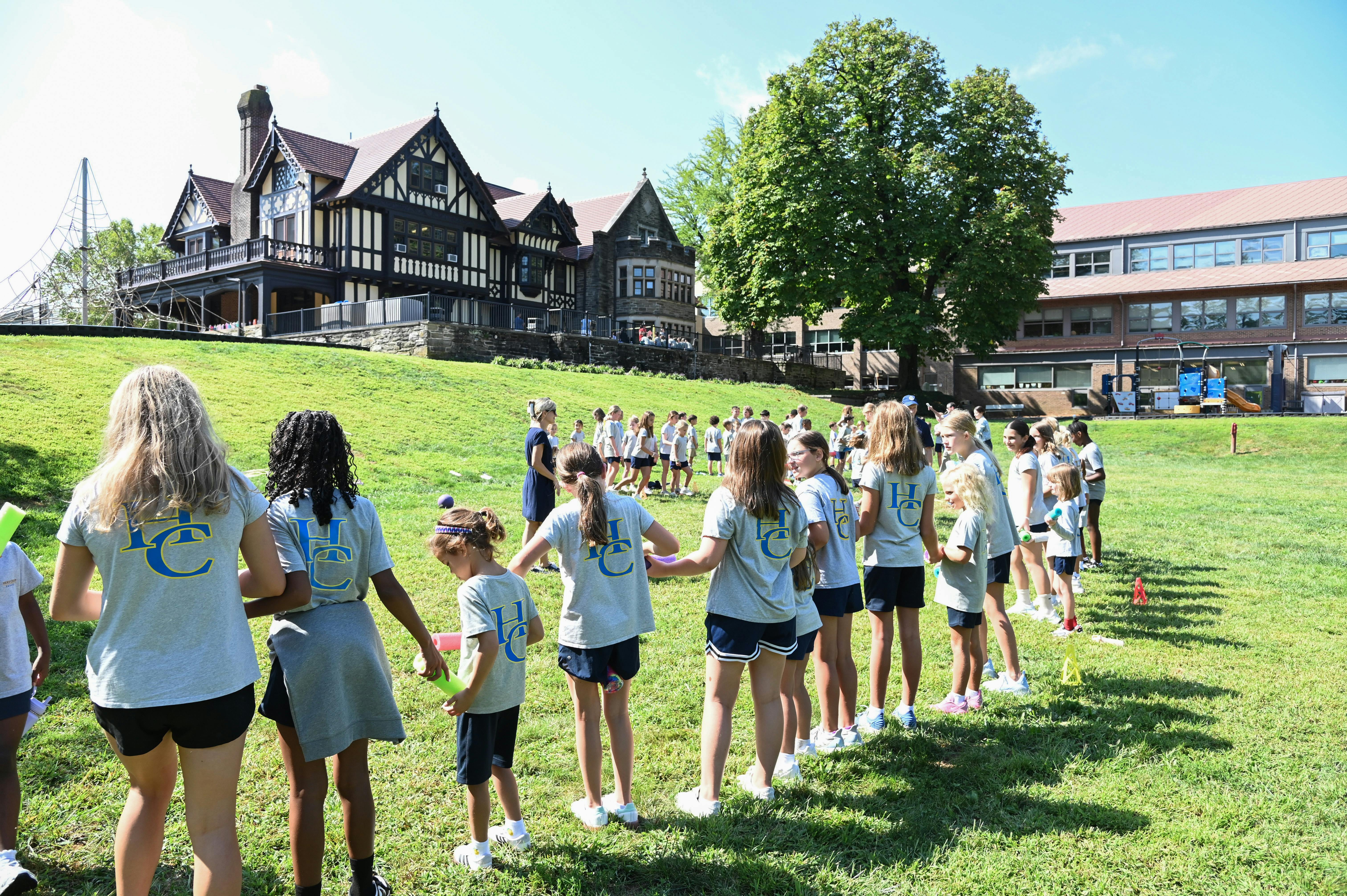Group of children holding hands in a line on a grassy field