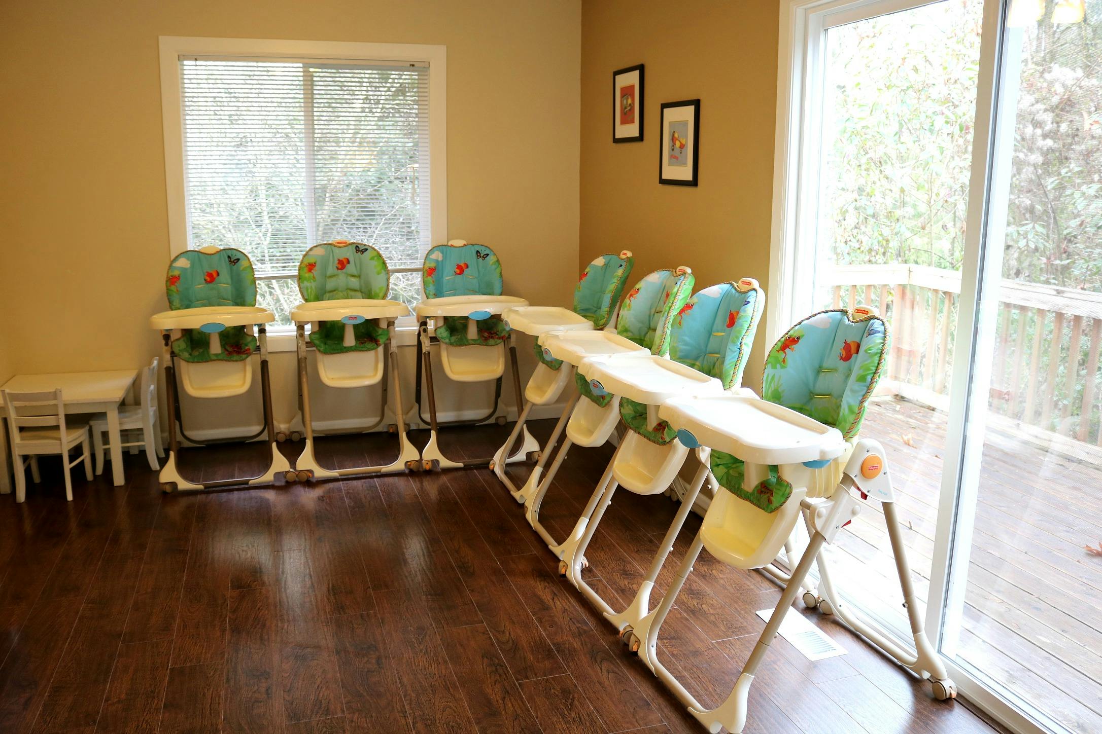 Row of high chairs in a room with a window and glass door