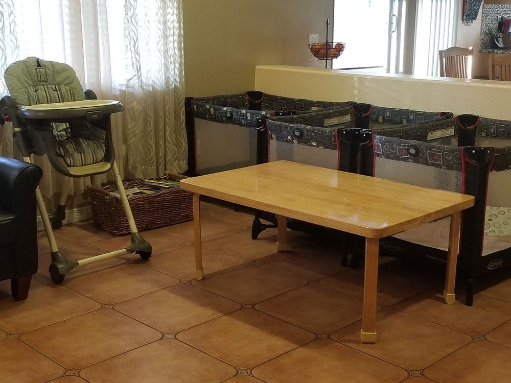 High chair, wooden table, and multiple cribs in a room