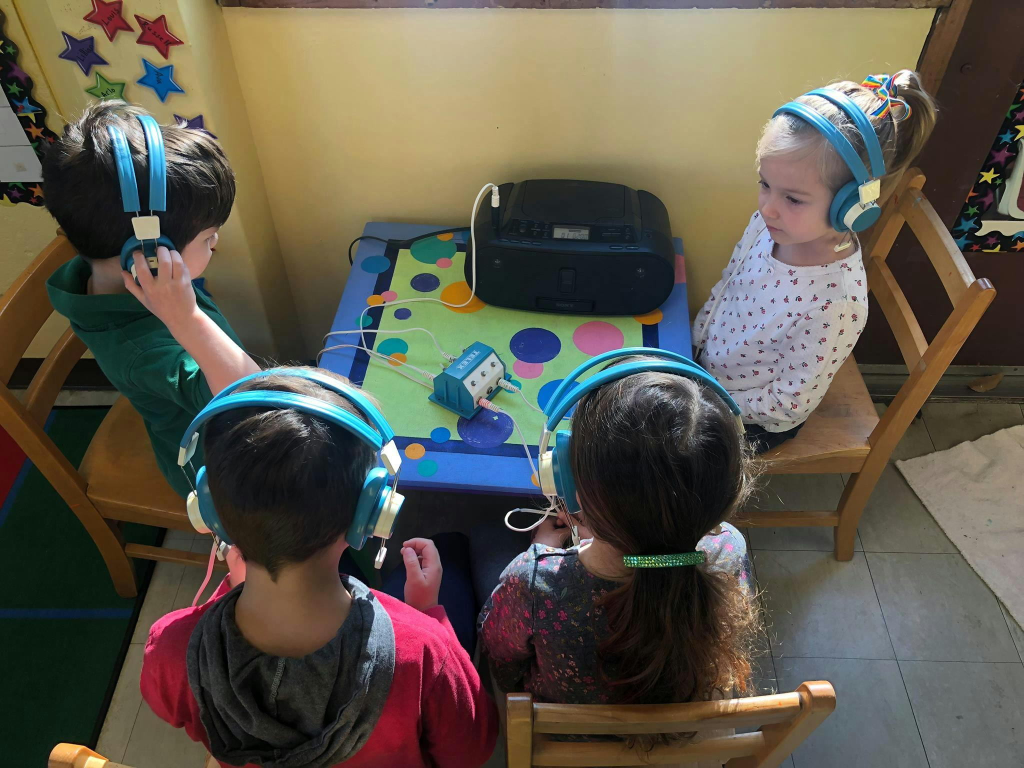 Four children wearing headphones around a small table