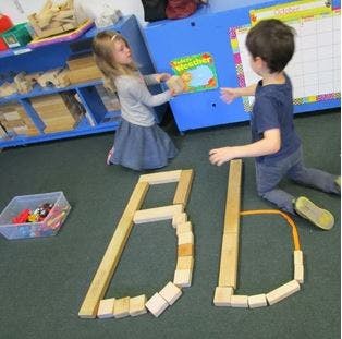 Two children playing with blocks in a classroom