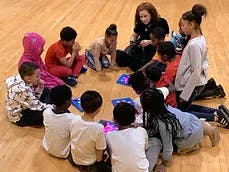 Adult and children sitting in a circle on a wooden floor