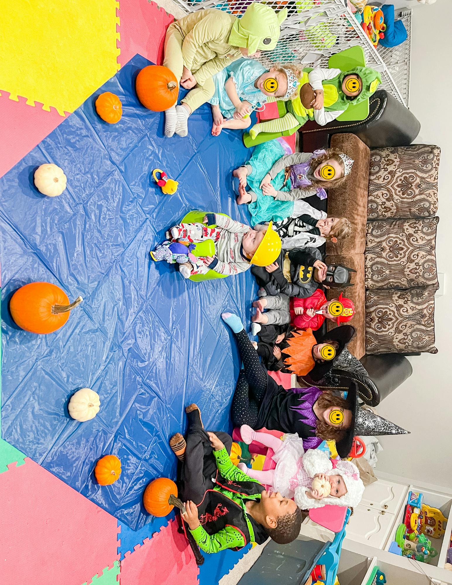 Children in various costumes playing on a blue mat with pumpkins