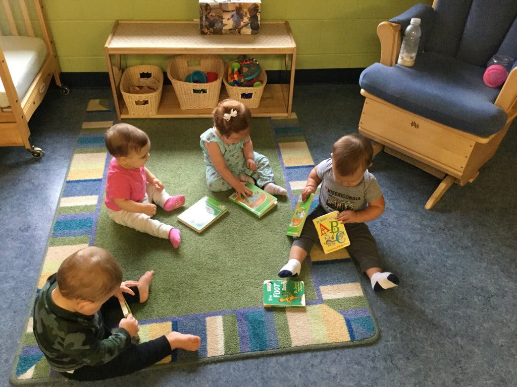 Four children sitting on a rug with books in a classroom