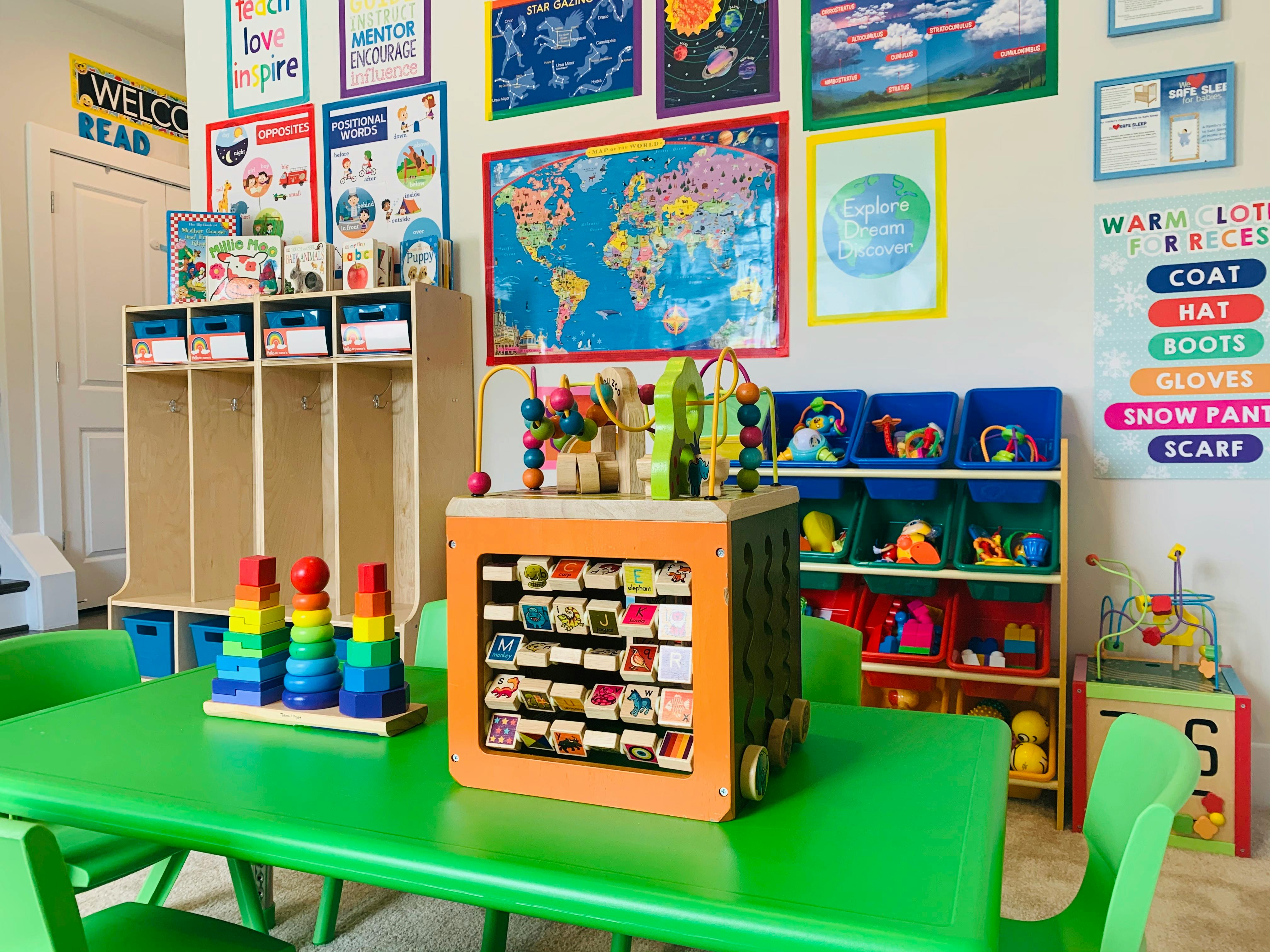 Classroom with green tables, cubbies, and educational posters on the wall