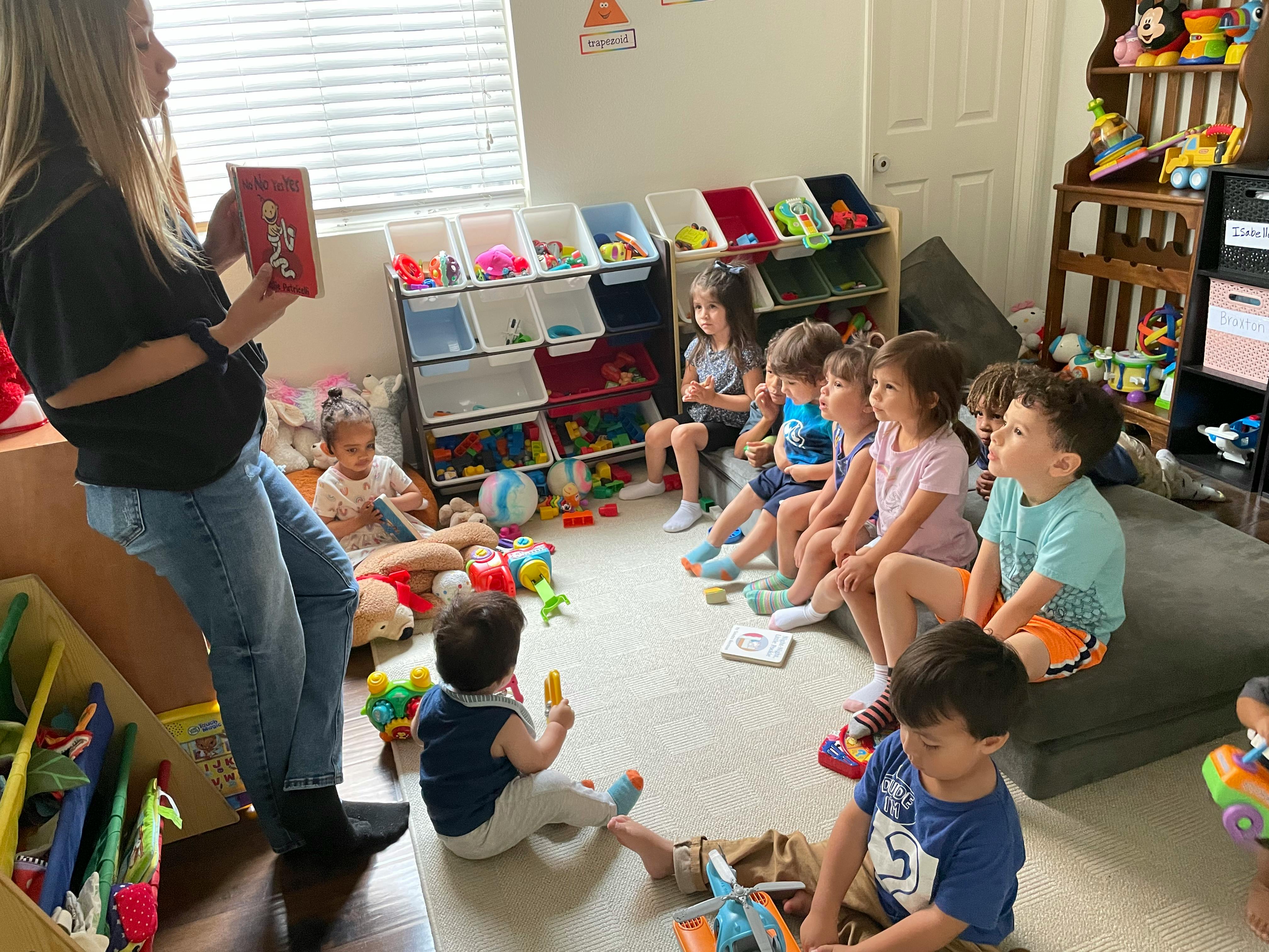 Person reading a book to a group of children in a classroom