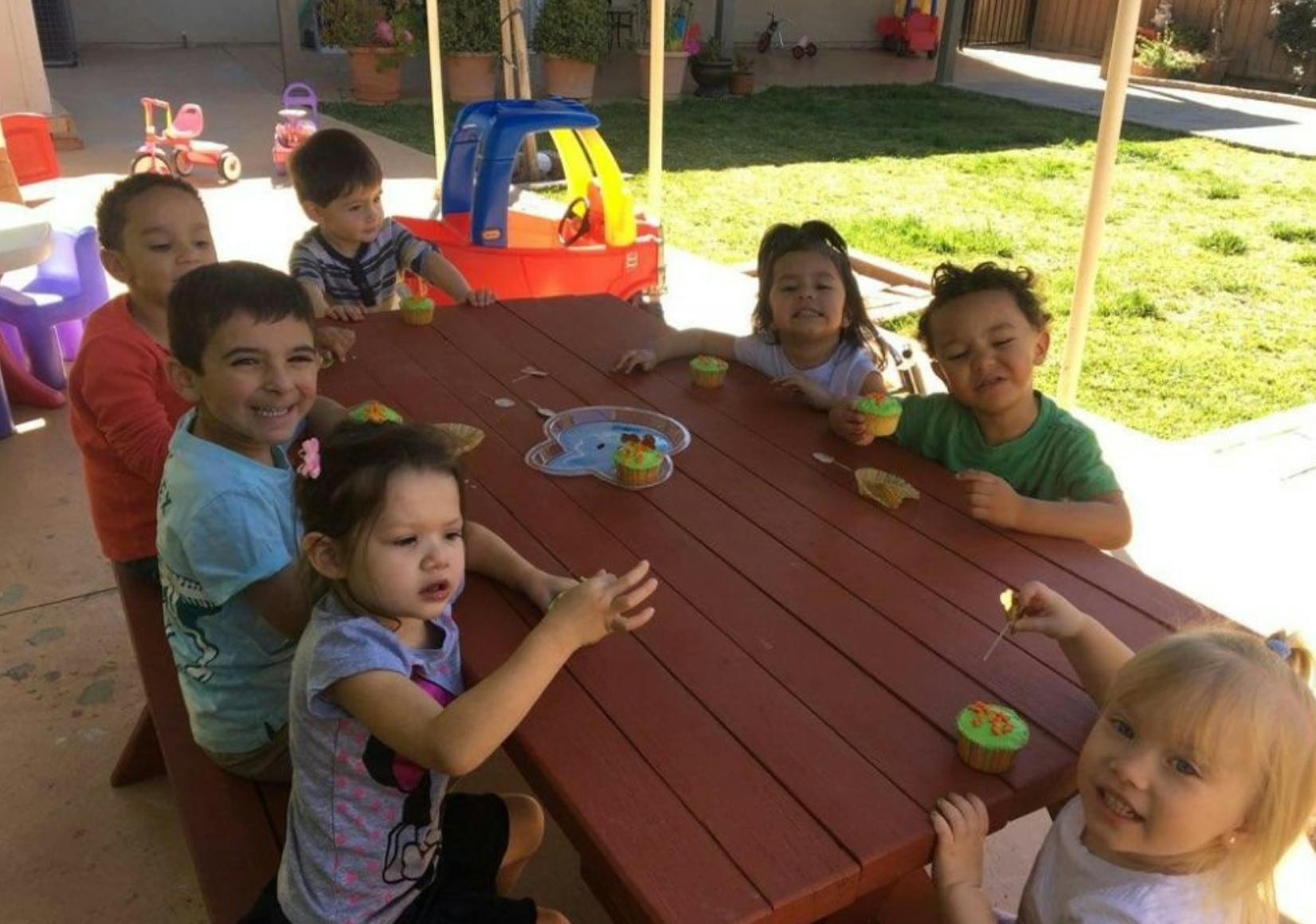 Children sitting around a picnic table outdoors