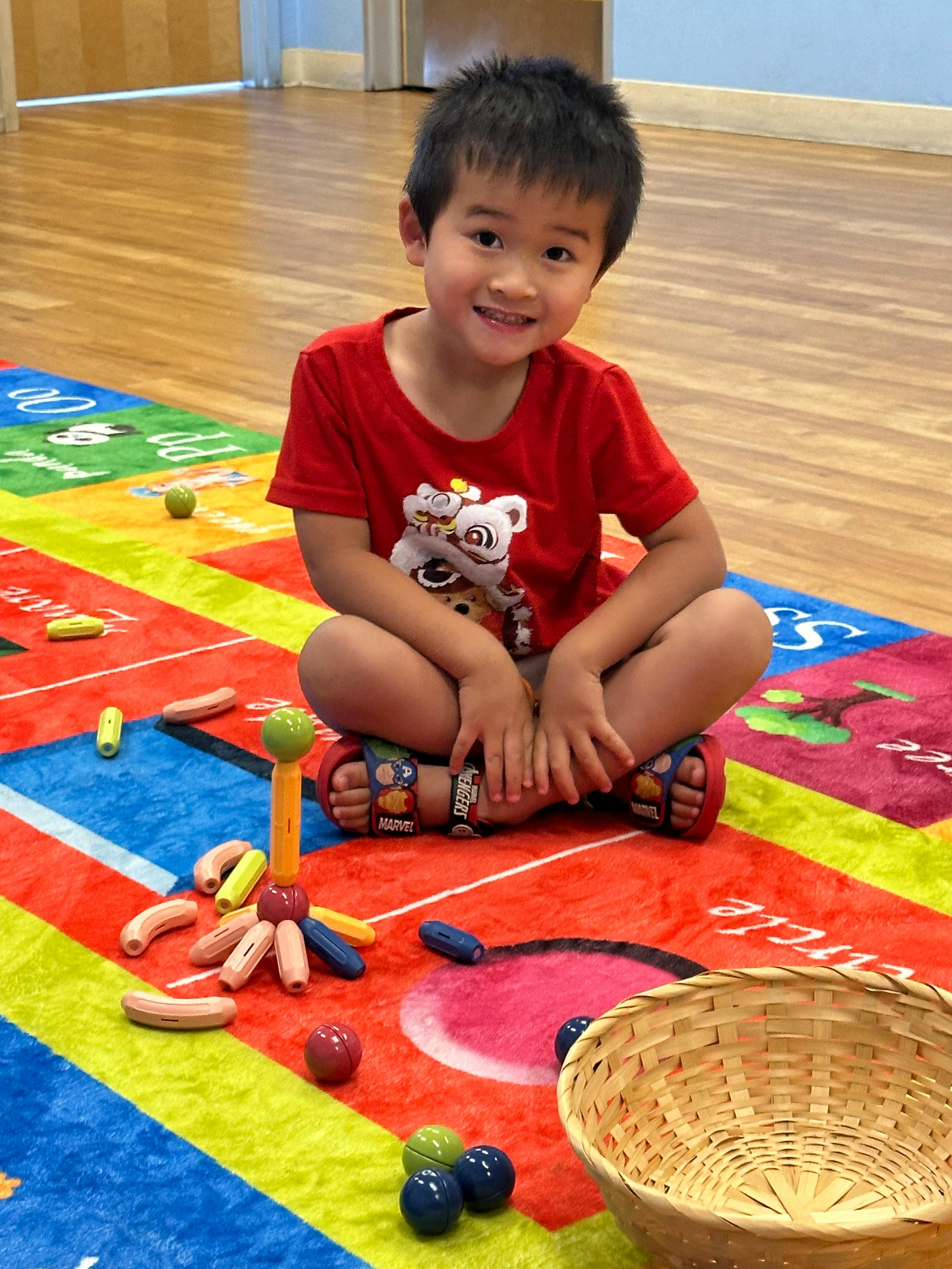Child sitting on a colorful rug with toys