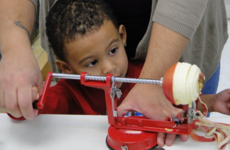 Child and person using an apple peeler