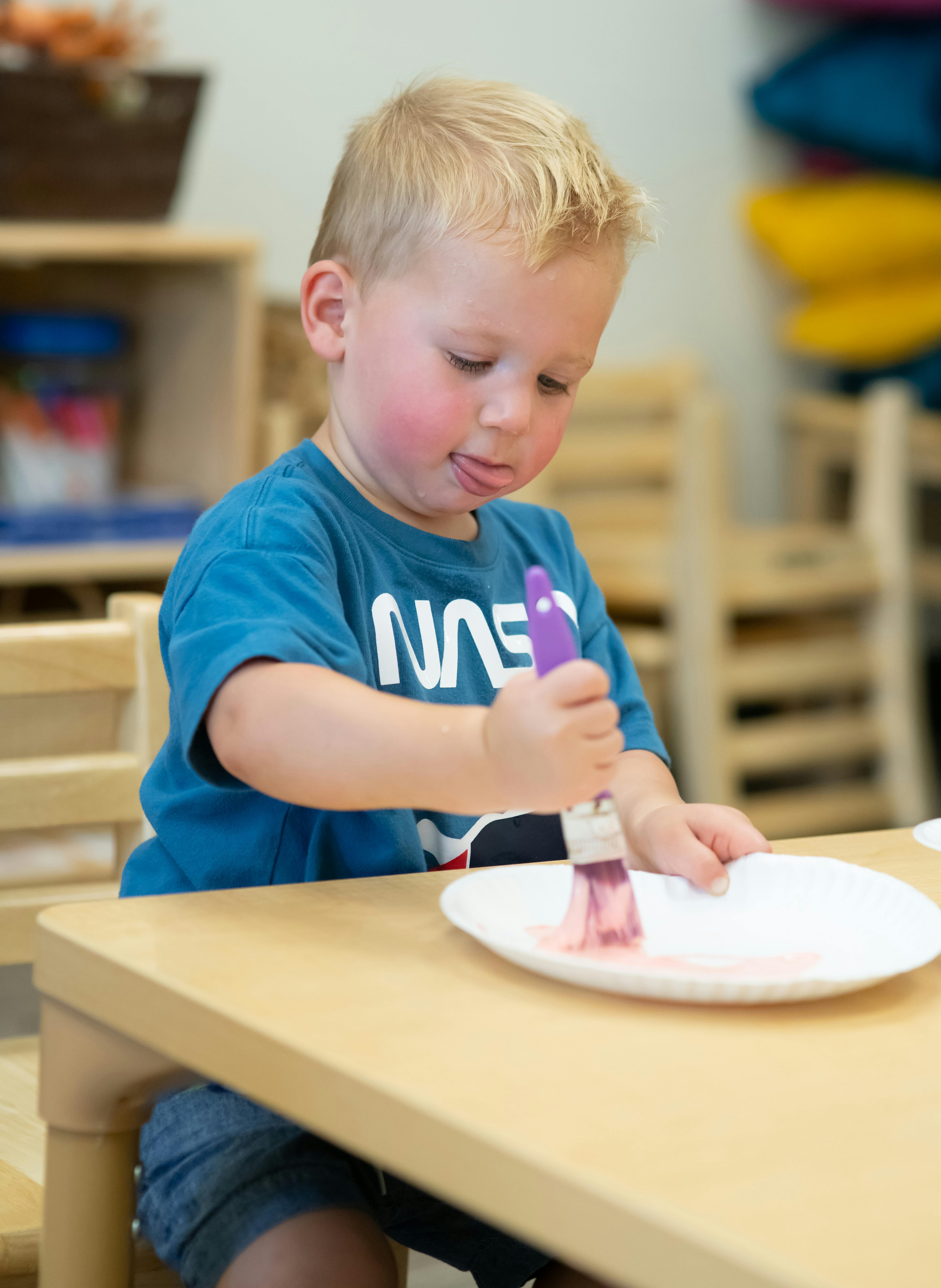 Child painting on a paper plate at a table