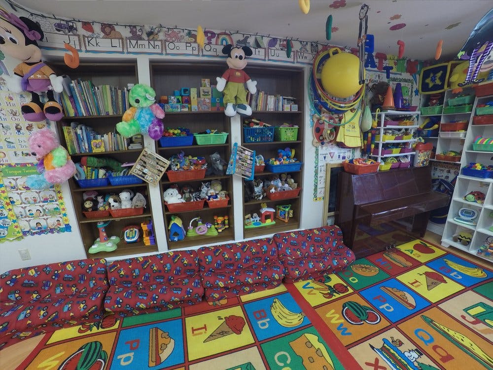 Playroom with shelves of toys, a colorful alphabet rug, and a piano