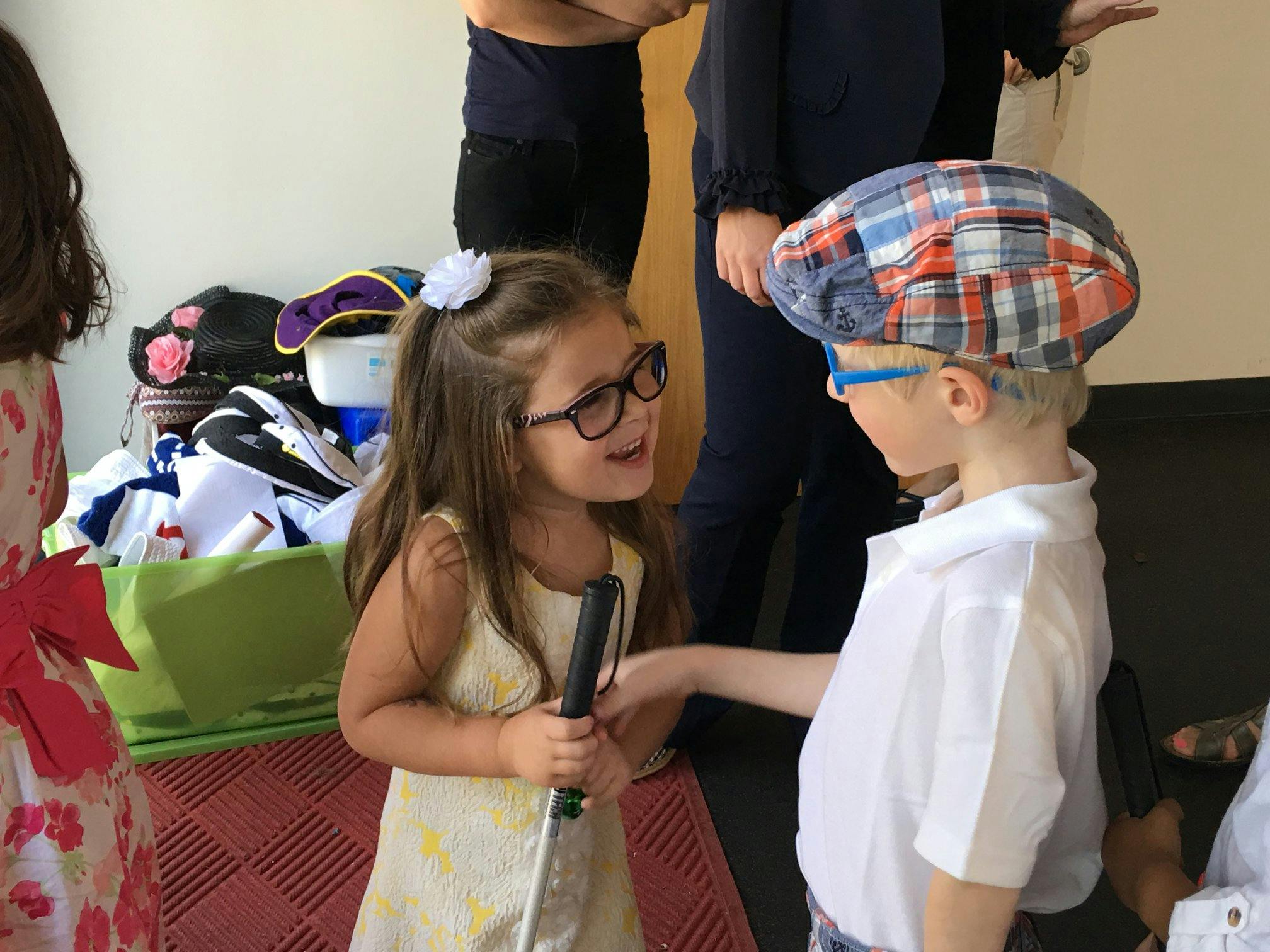 Child in glasses holding a microphone talking to another child in a plaid hat