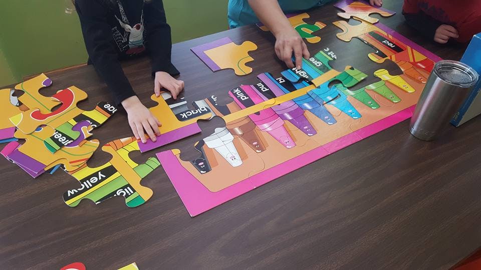 People assembling a colorful puzzle on a table