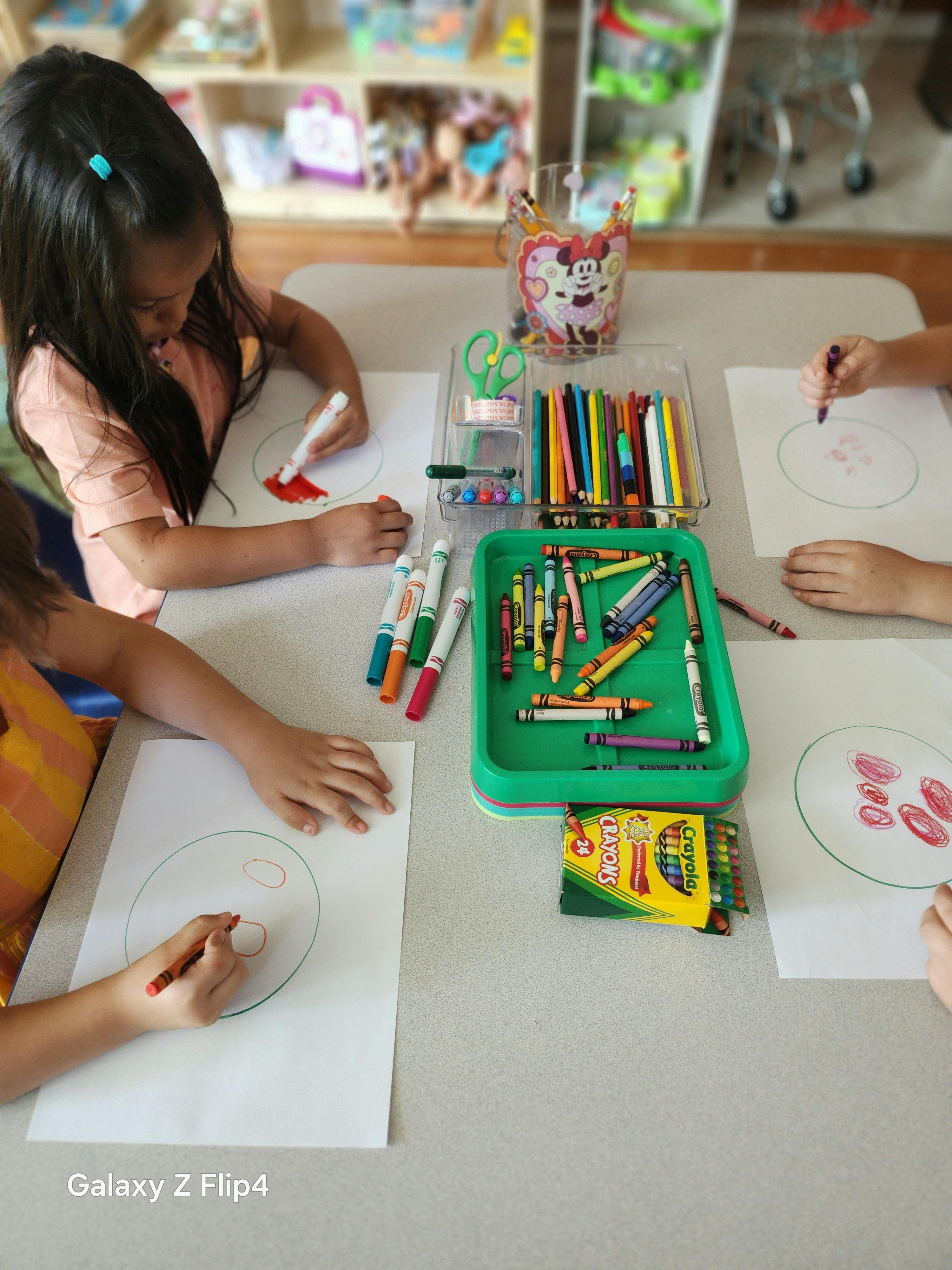Children drawing at a table with crayons and markers