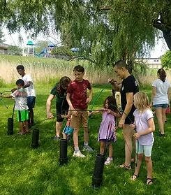 People and children practicing archery outdoors