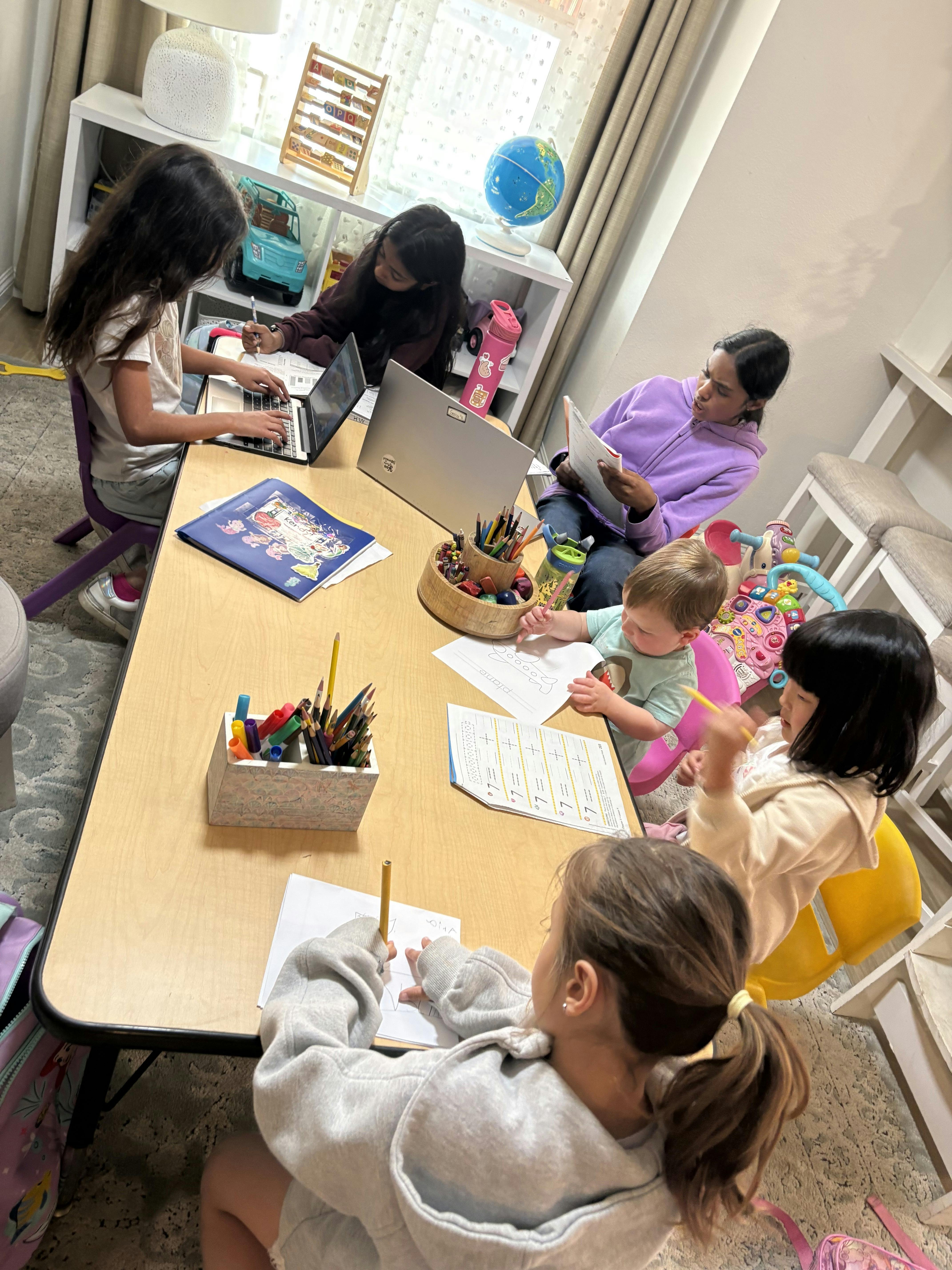 Children doing homework and drawing at a long table