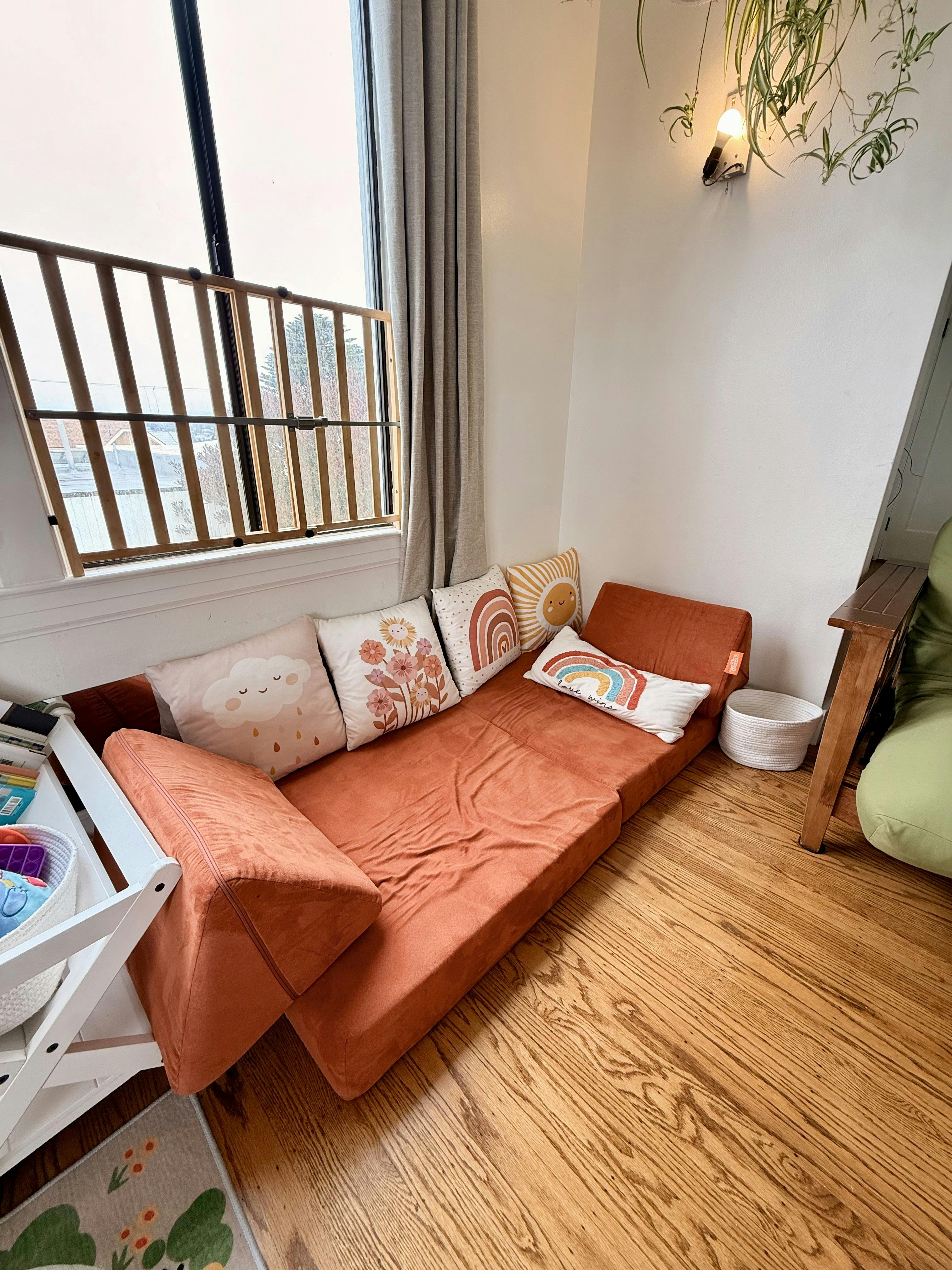 Orange modular play couch with decorative pillows in a child playroom