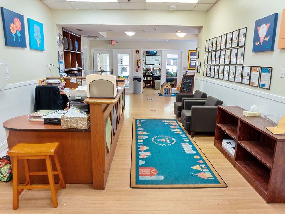 An empty reception area with a desk, two armchairs, and a patterned rug