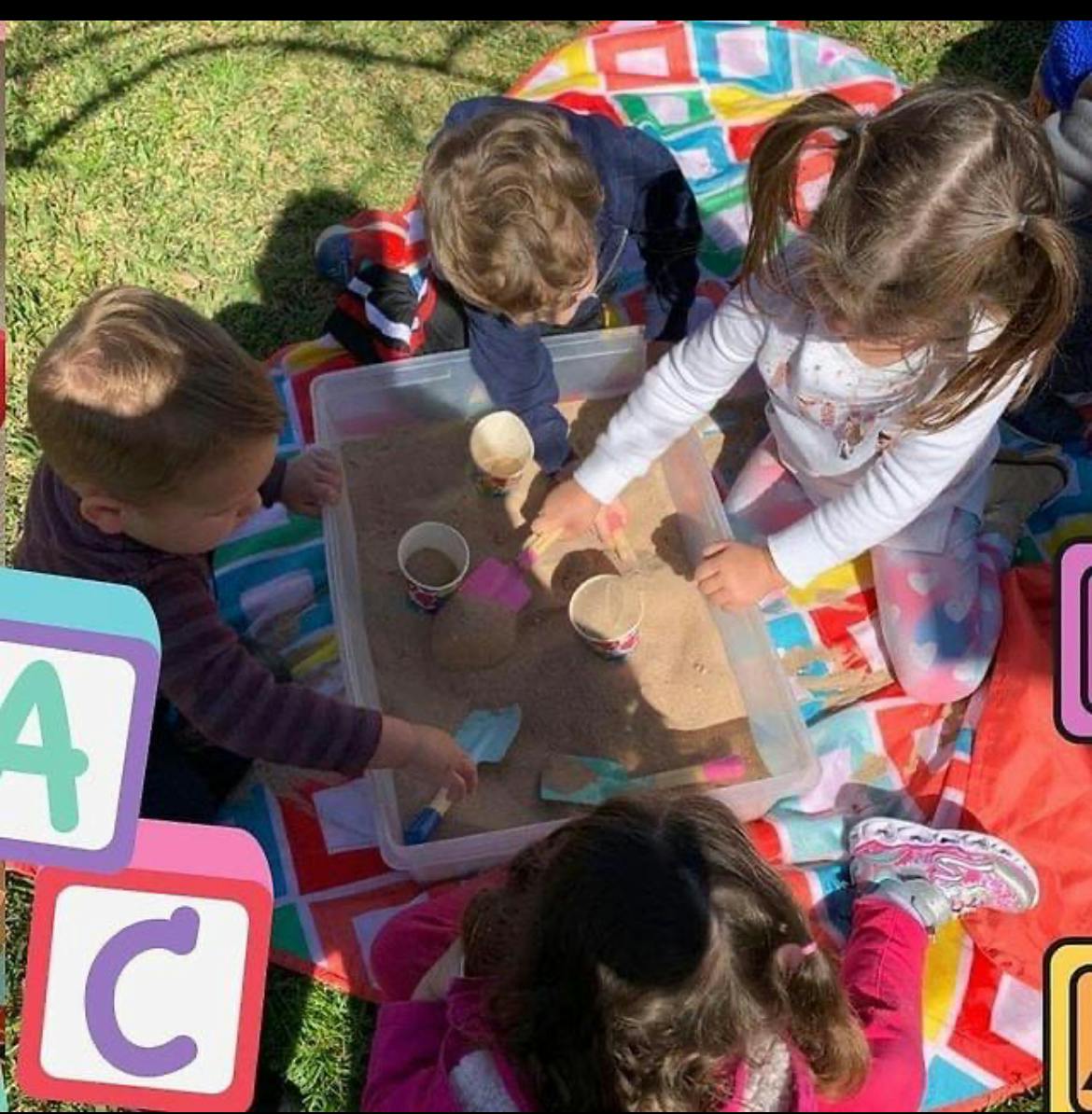 Children playing with sand in a container outdoors