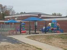 Playground with blue shade structures and a brick building in the background