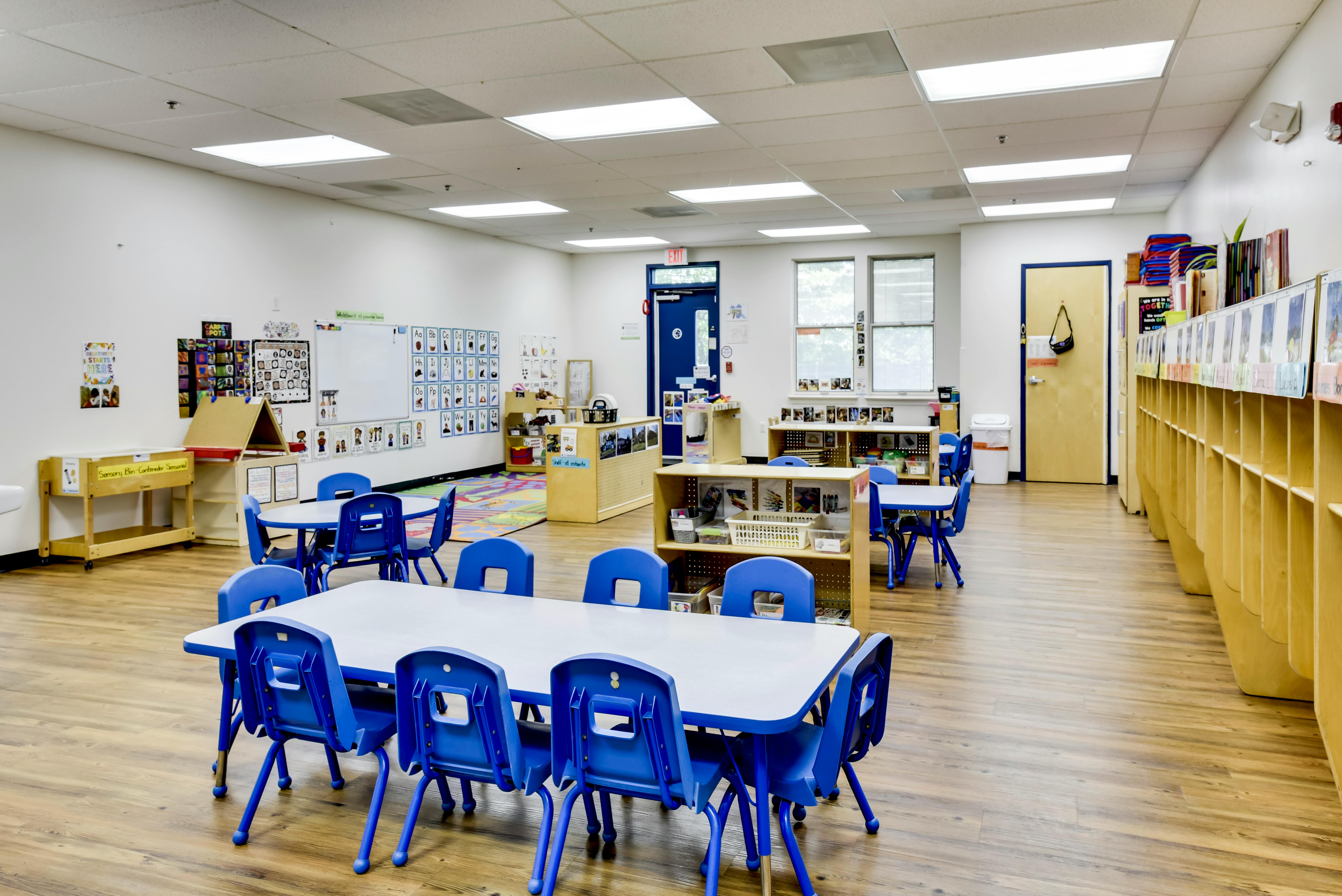 Empty preschool classroom with tables and blue chairs