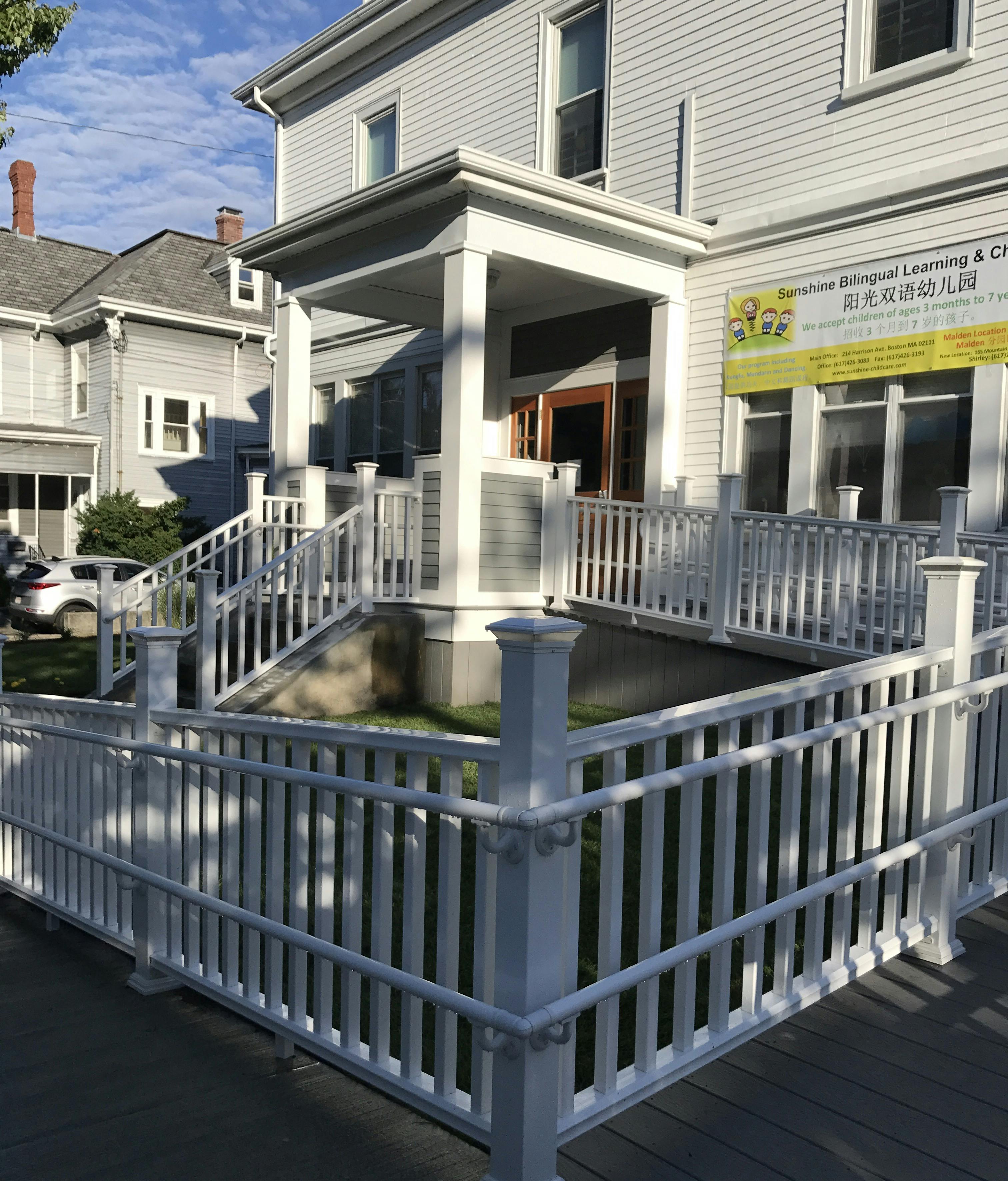 Building exterior with a porch, stairs, and a ramp with white railings