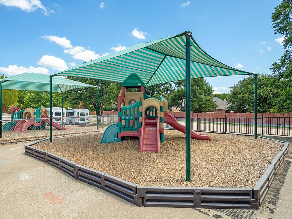 Playground with climbing structure, slides, and striped shade covers
