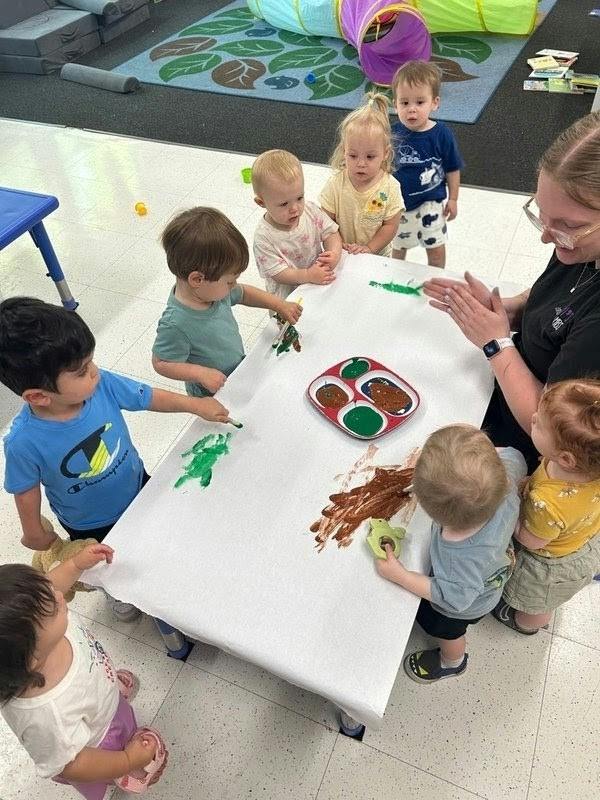 Group of children painting with an adult at a classroom table