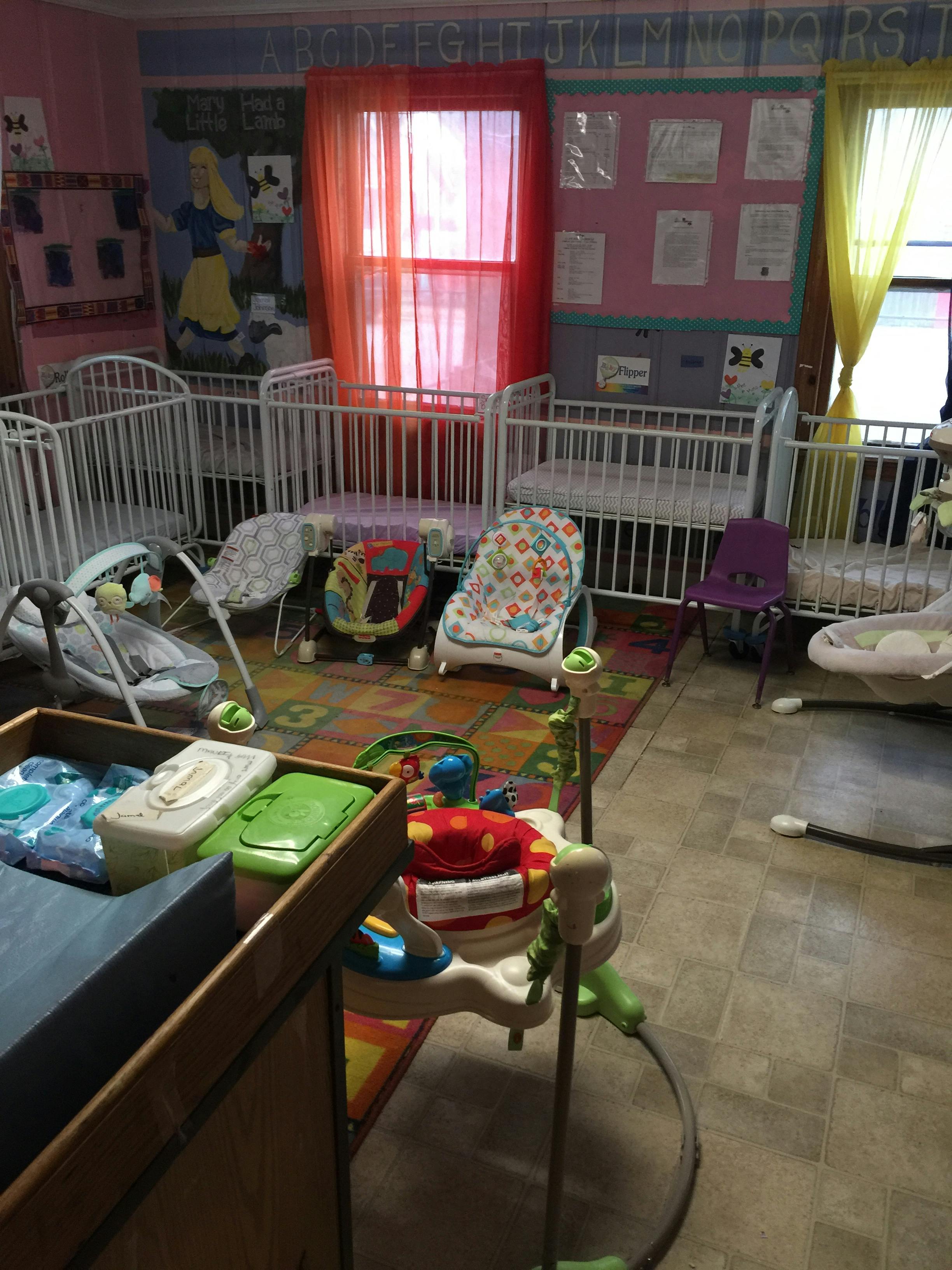 Nursery room with multiple cribs, infant seats, and play mats