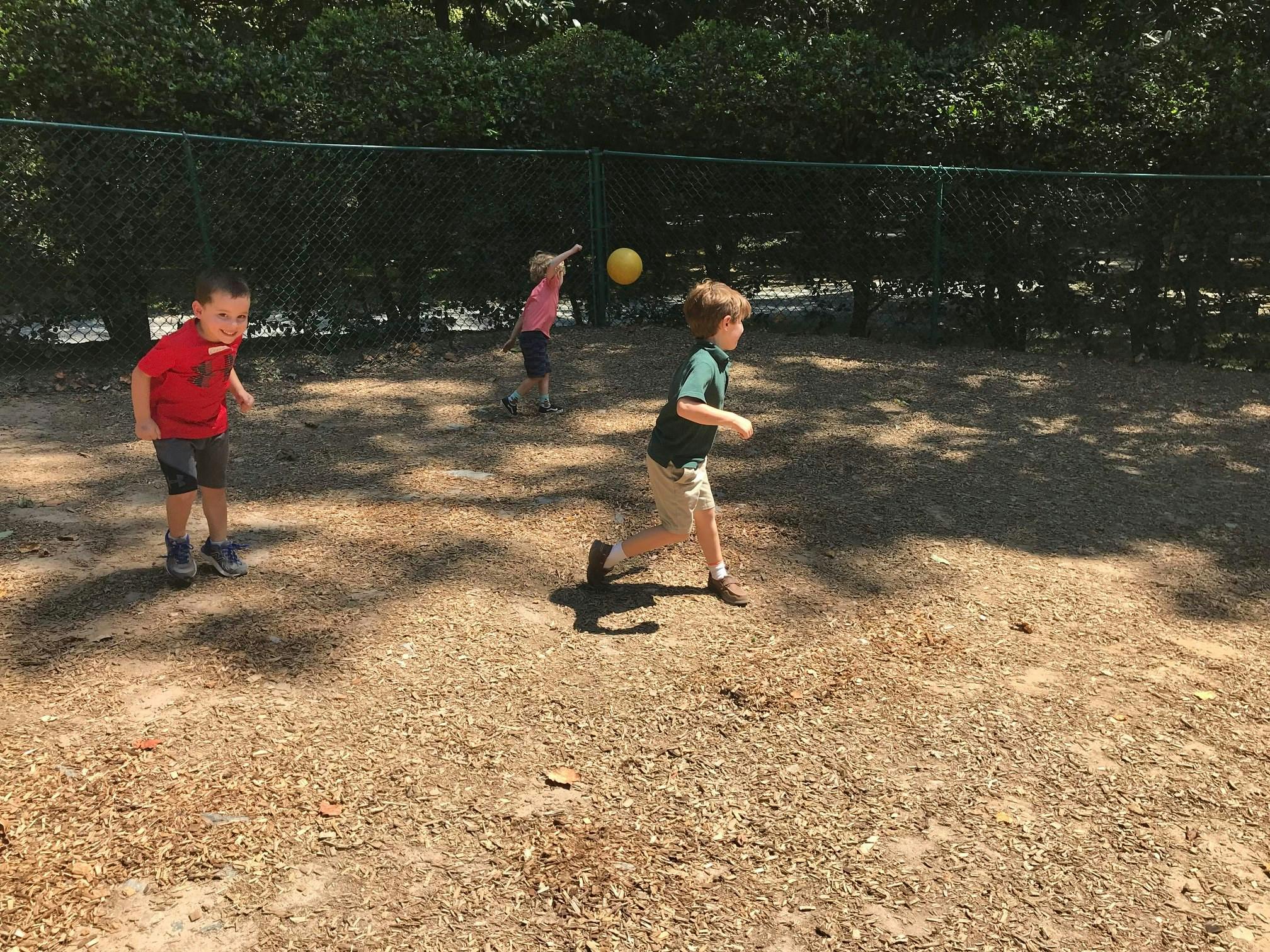 Three children playing with a yellow ball outdoors