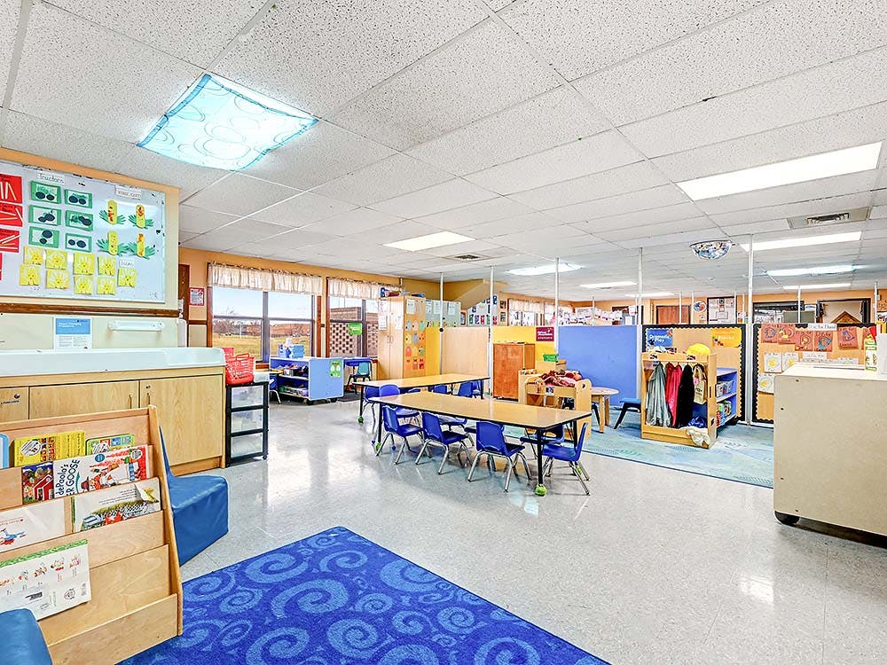 An empty classroom with small tables and chairs