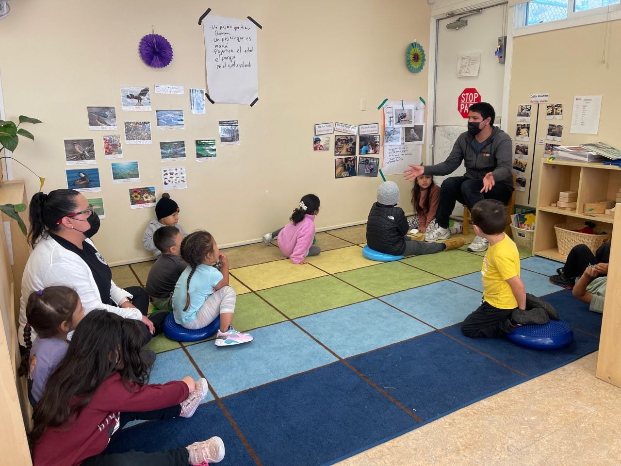 Adults and children sitting on floor in classroom